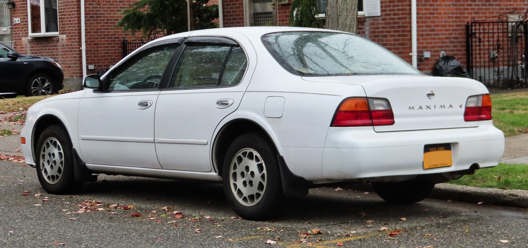 White sedan side profile and rear with distinct taillights and alloy wheels
