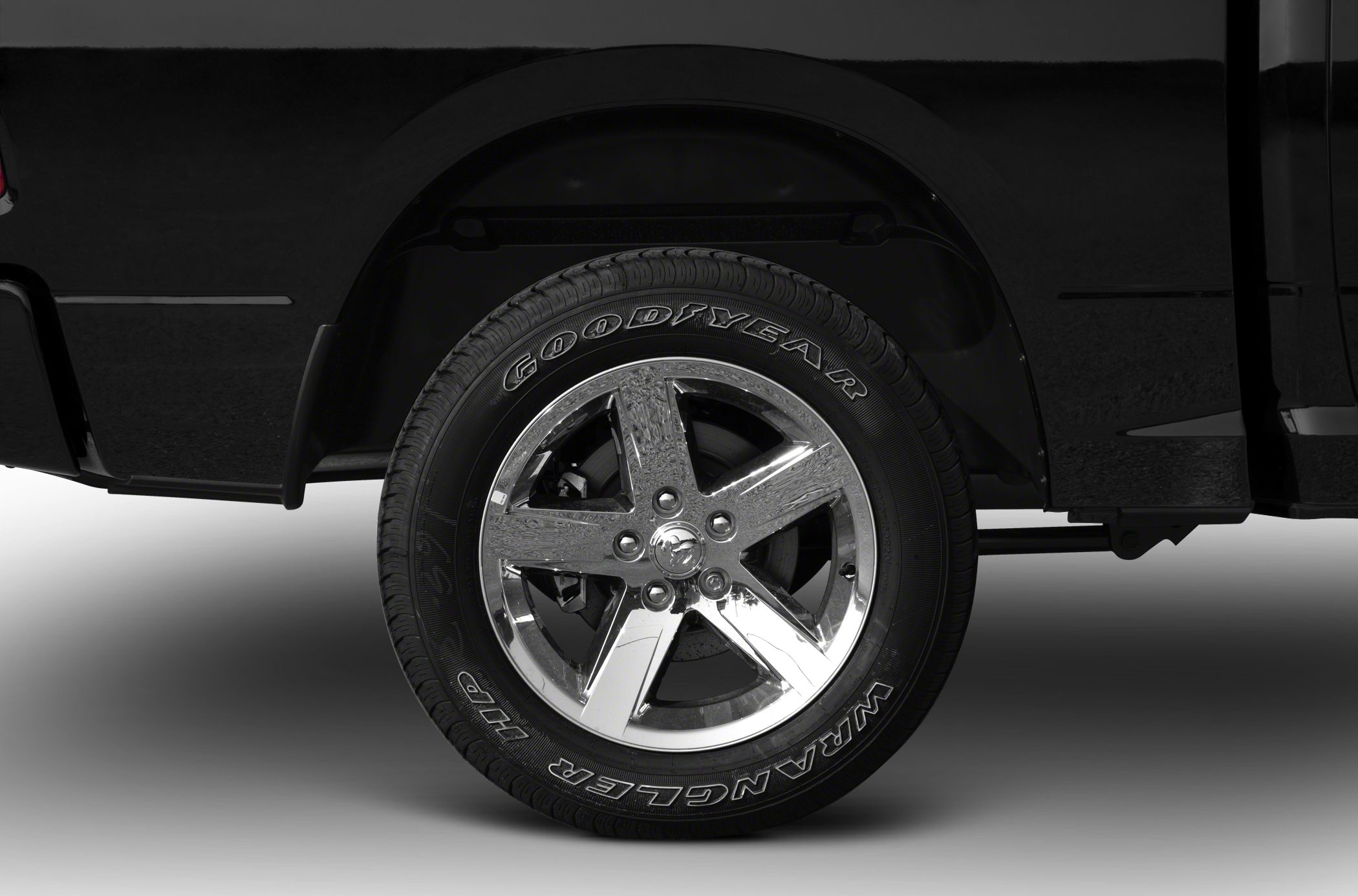 Chrome five-spoke alloy wheel with Goodyear Wrangler tire on black truck fender