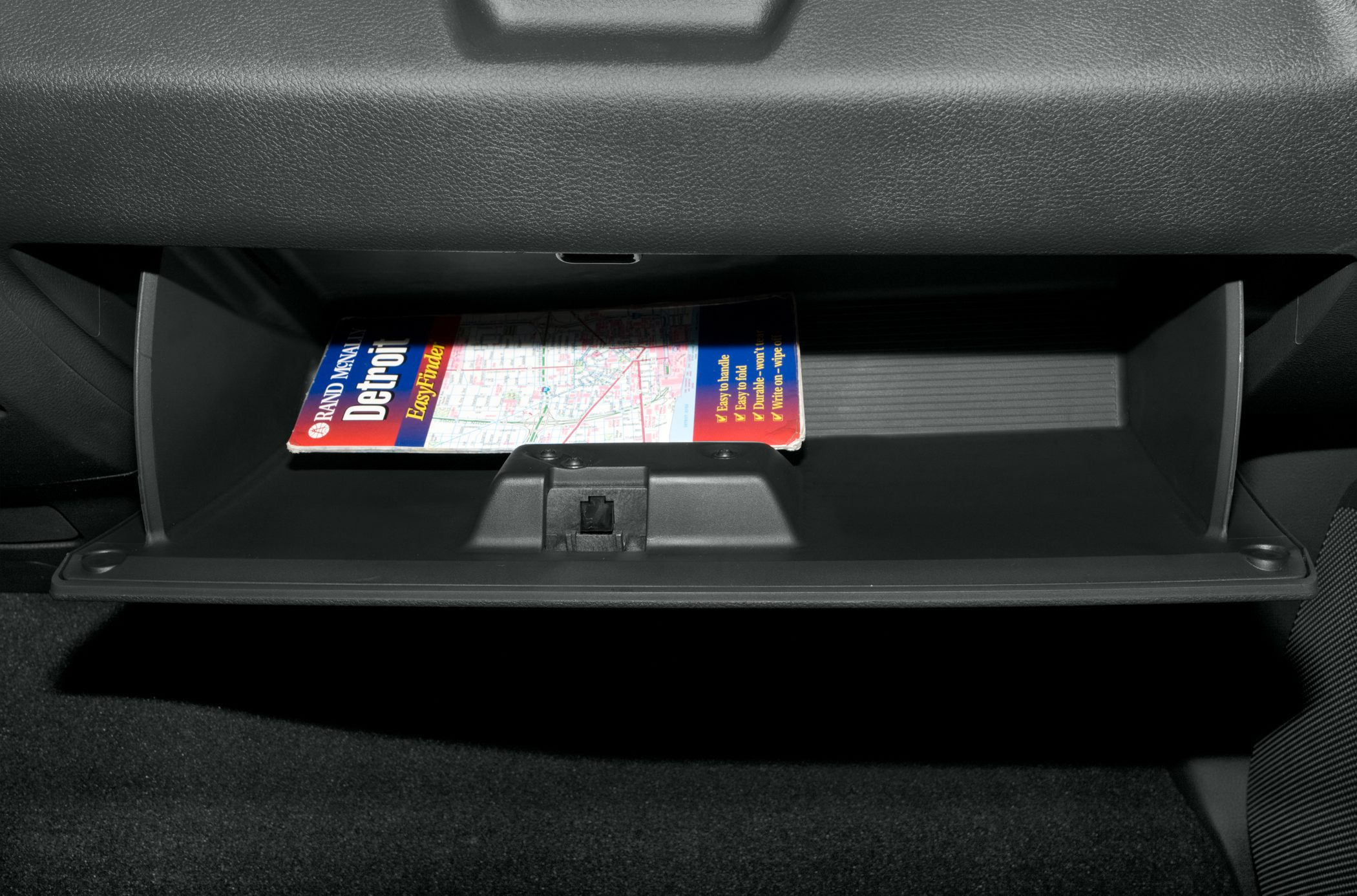 Open glovebox compartment with a map inside.