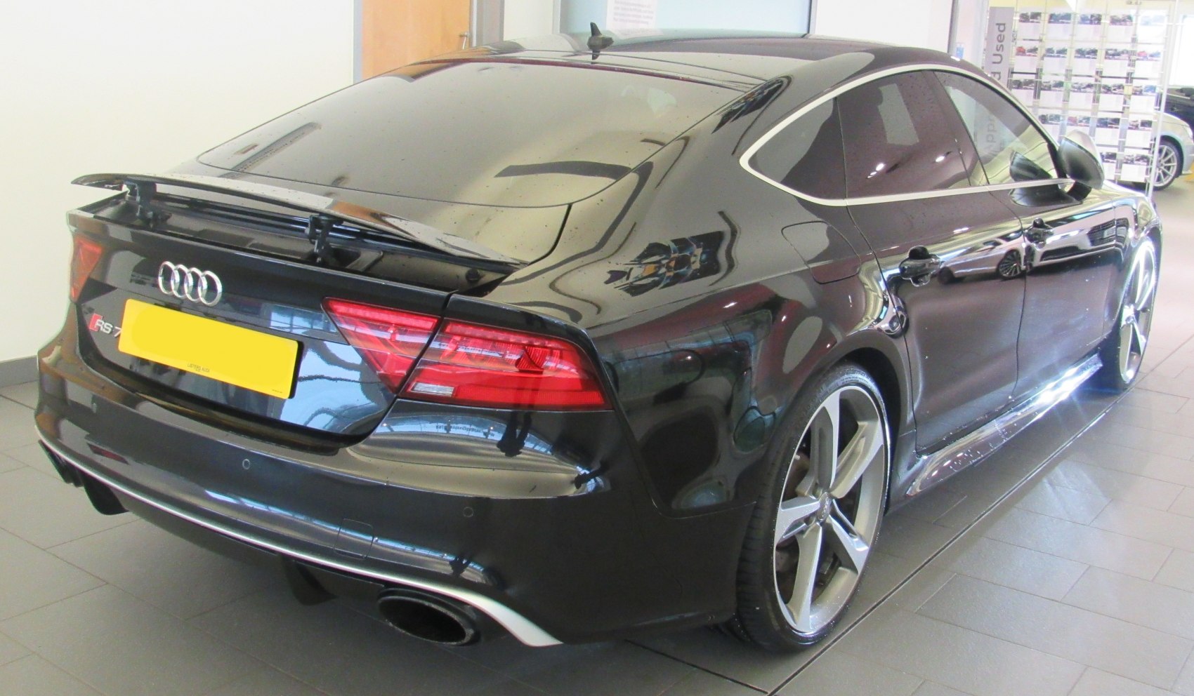 Rear-side view with spoiler, dual exhaust, and alloy wheels
