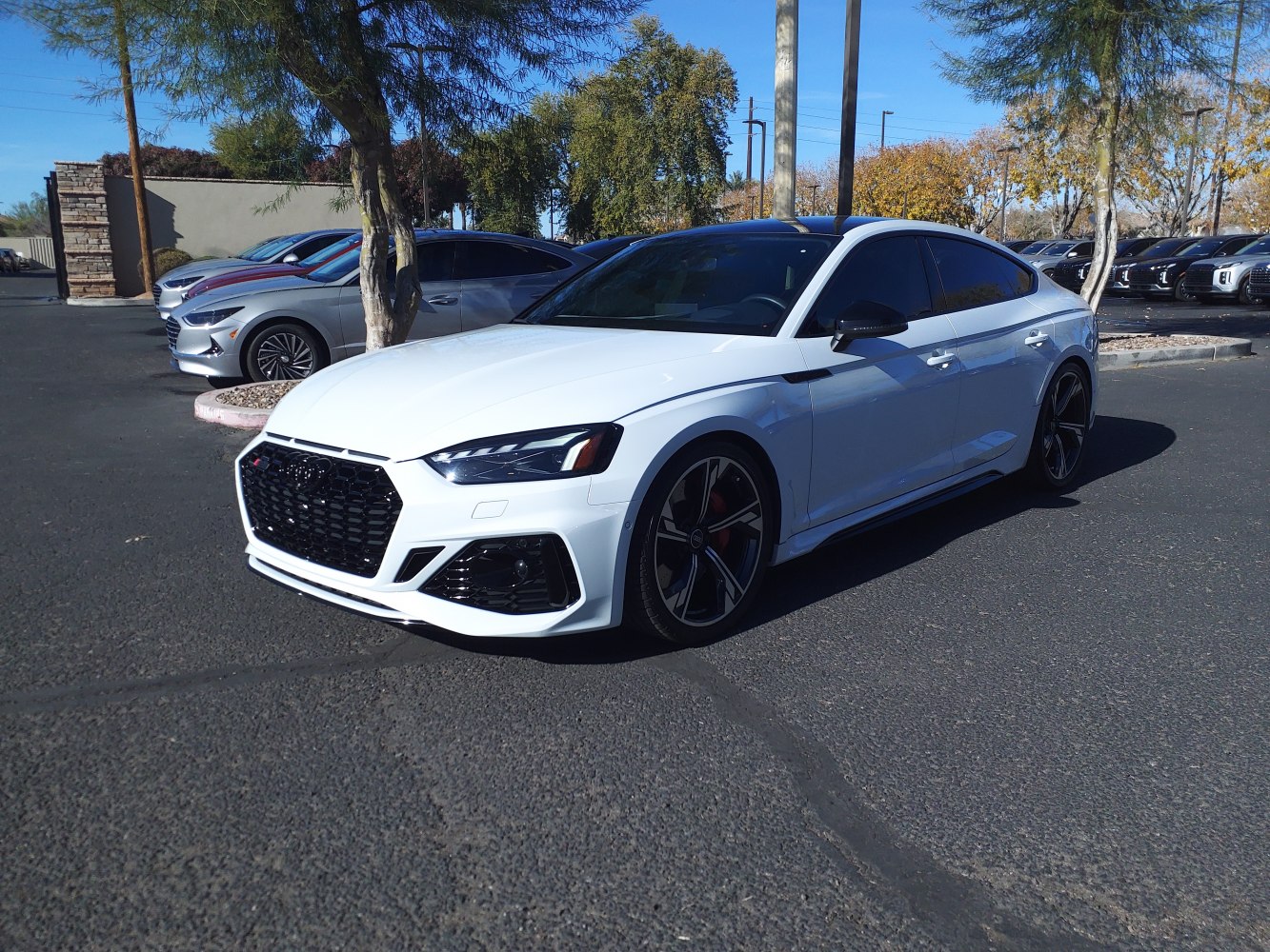 White sporty sedan with aggressive front grille and large alloy wheels