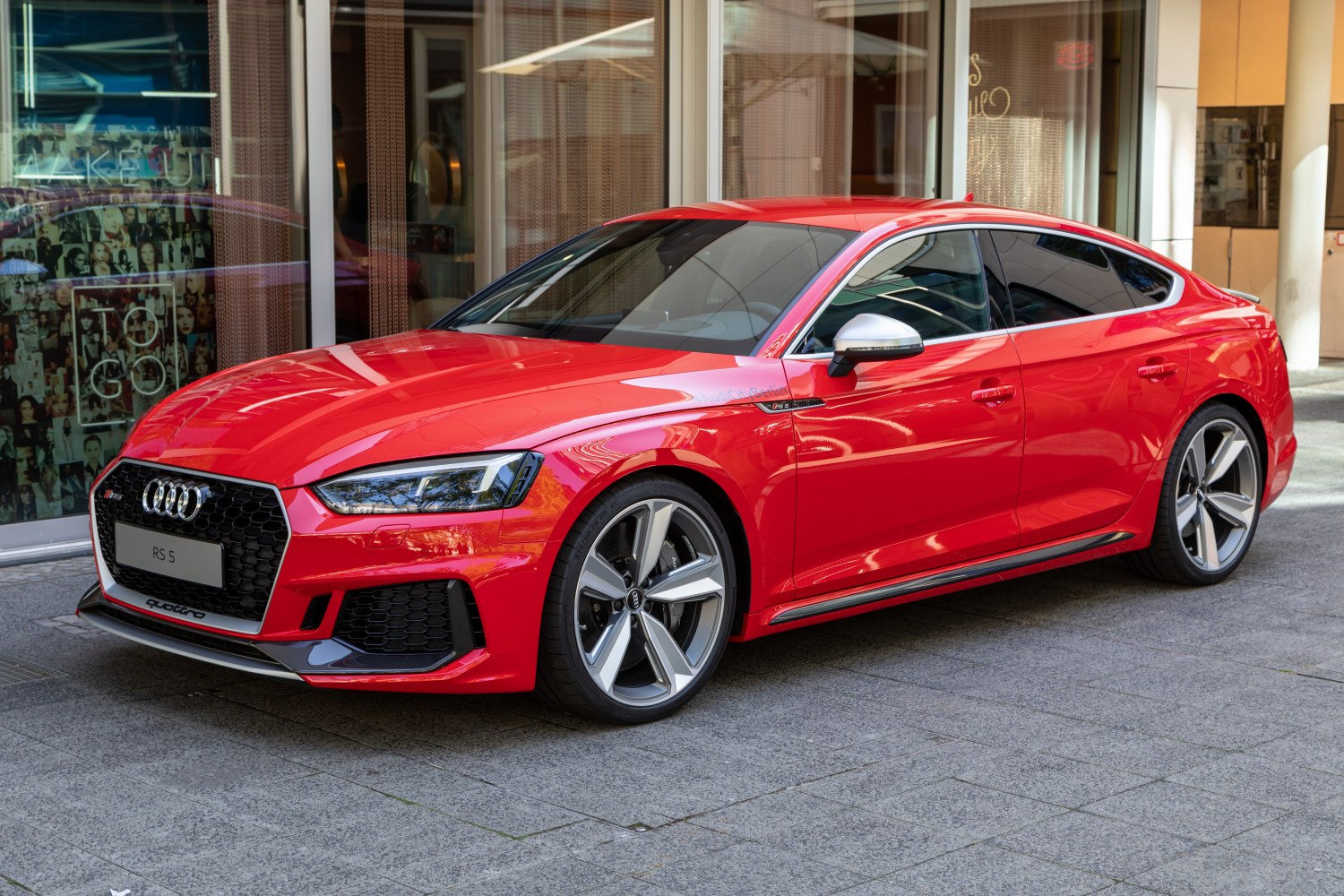 Red sporty coupe-style sedan front side with LED headlights and alloy wheels