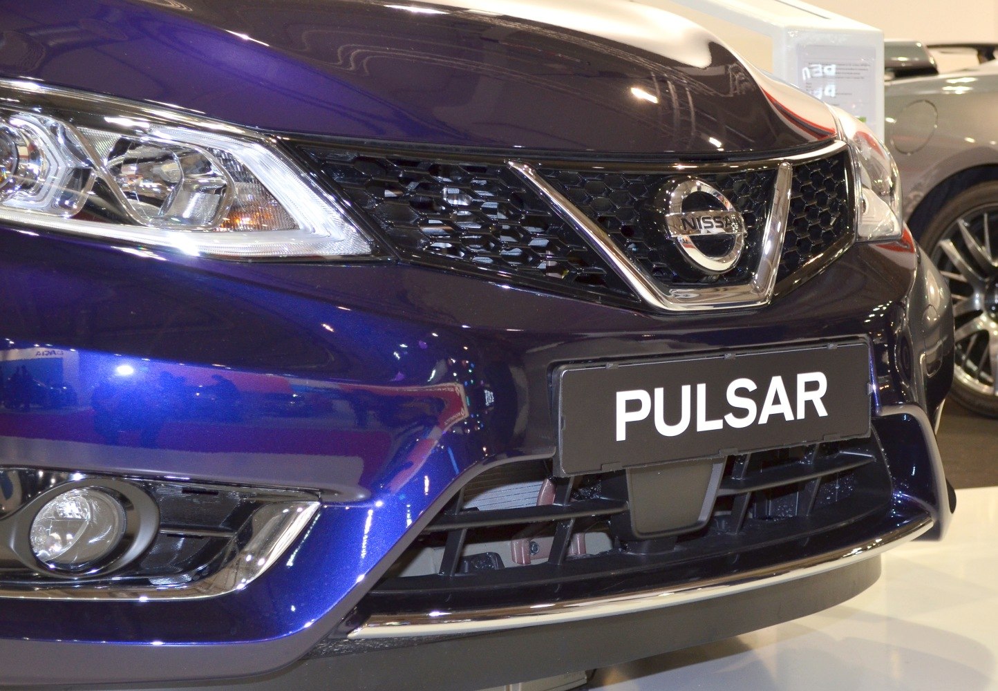 Close-up of front grille, headlight, fog light details with Nissan badge
