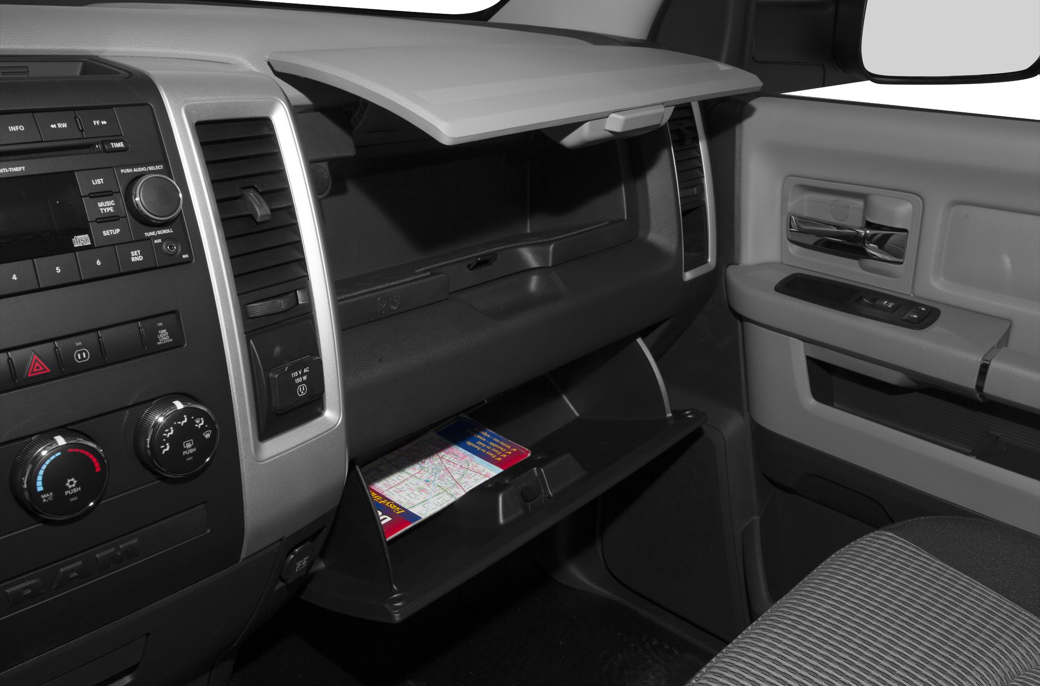 Dashboard center console and open glove compartment with map inside.