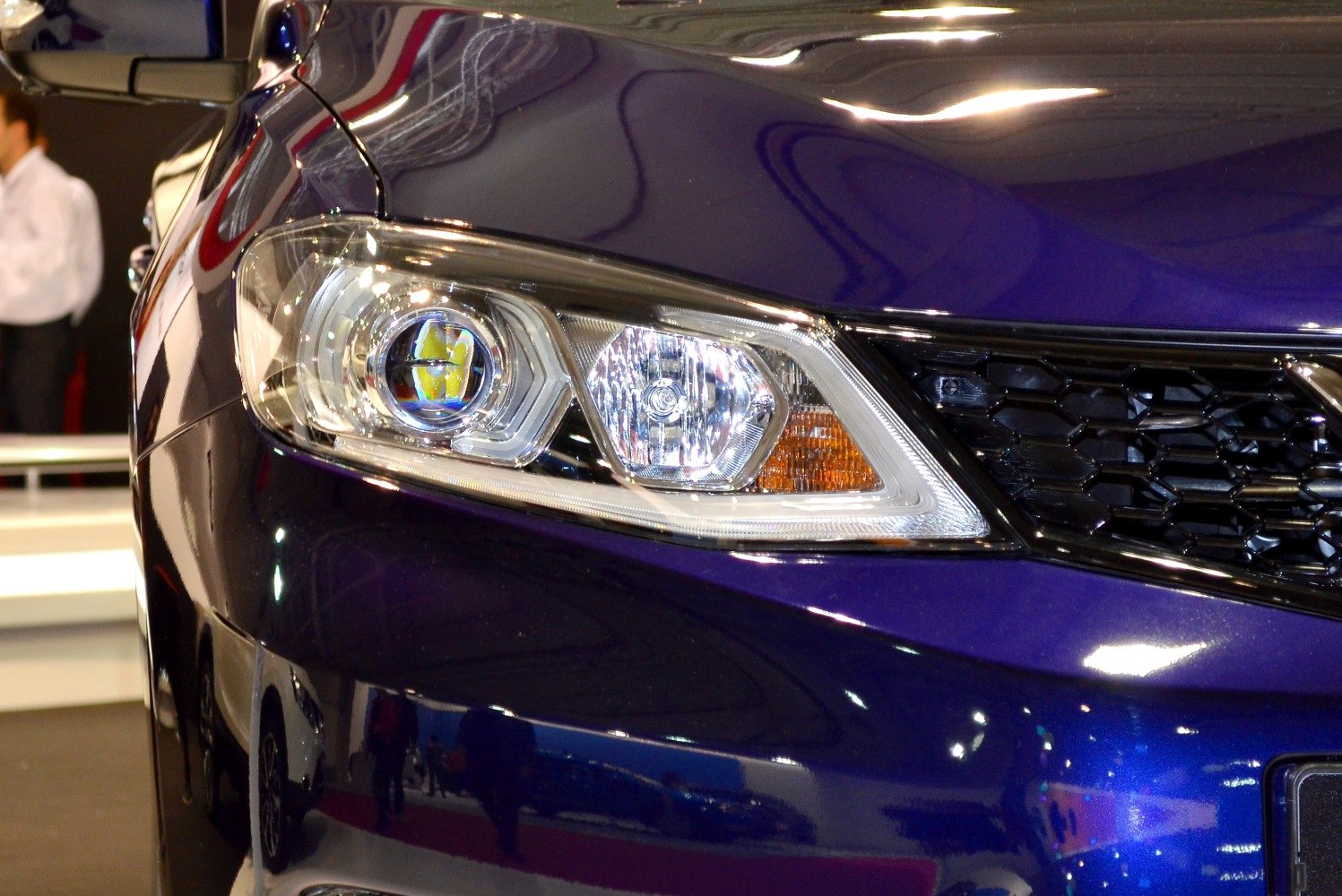 Close-up of front headlight and black honeycomb grille