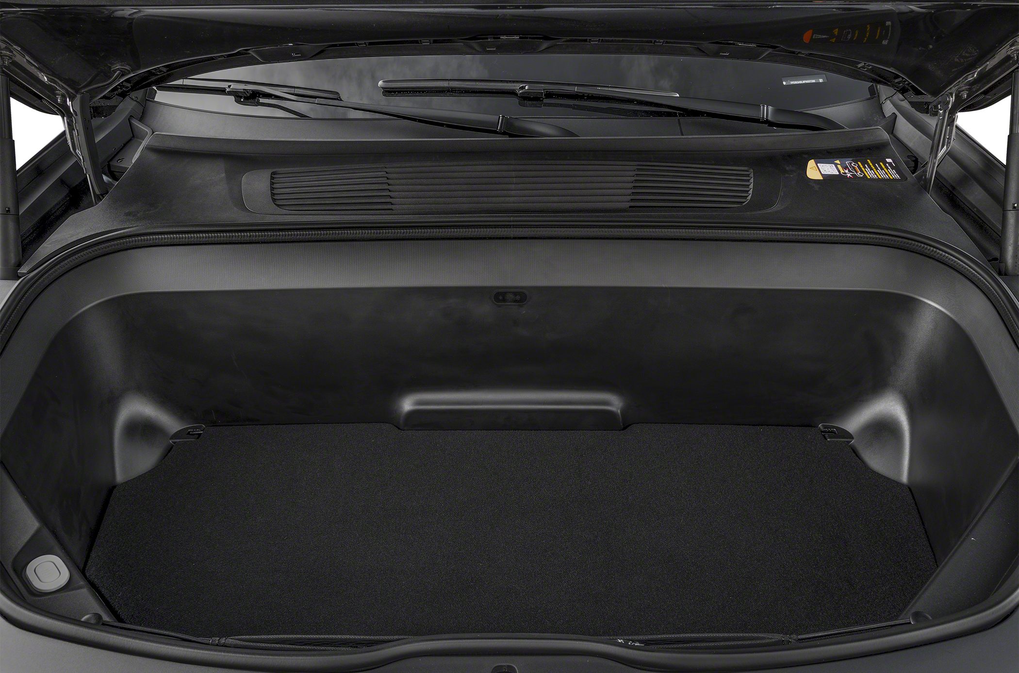 Spacious front trunk compartment with carpeted floor and clean black plastic walls.