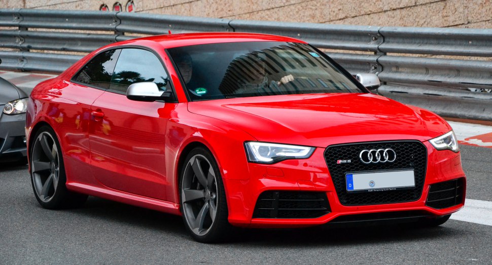 Red sporty coupe with aggressive headlights and large dark alloy wheels