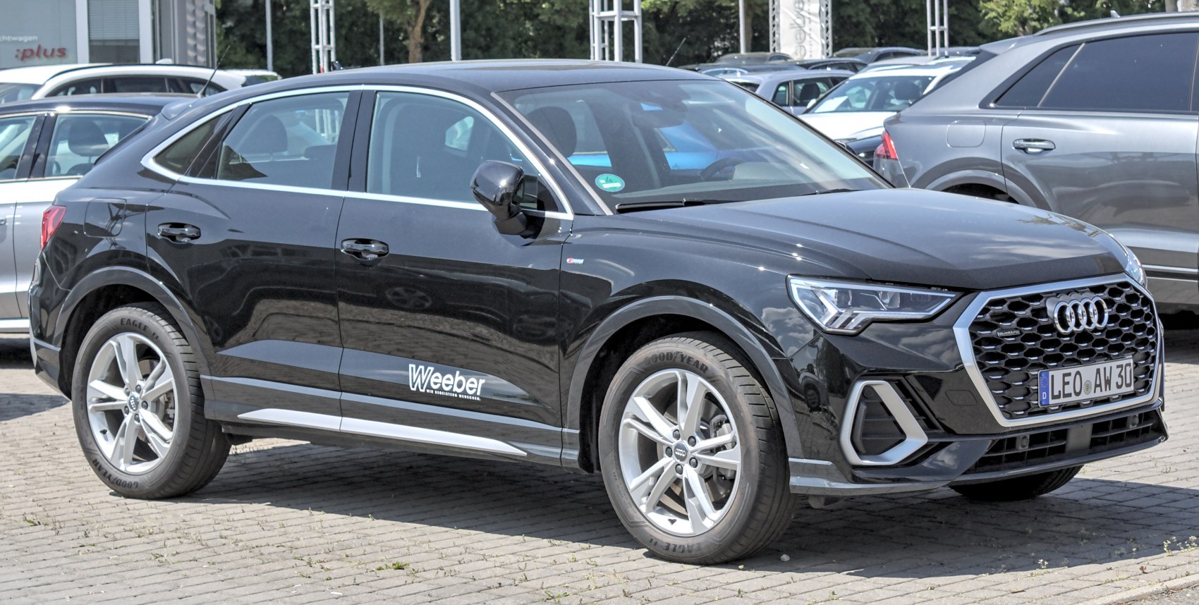 Front side view of a black SUV coupe with prominent grille and alloy wheels
