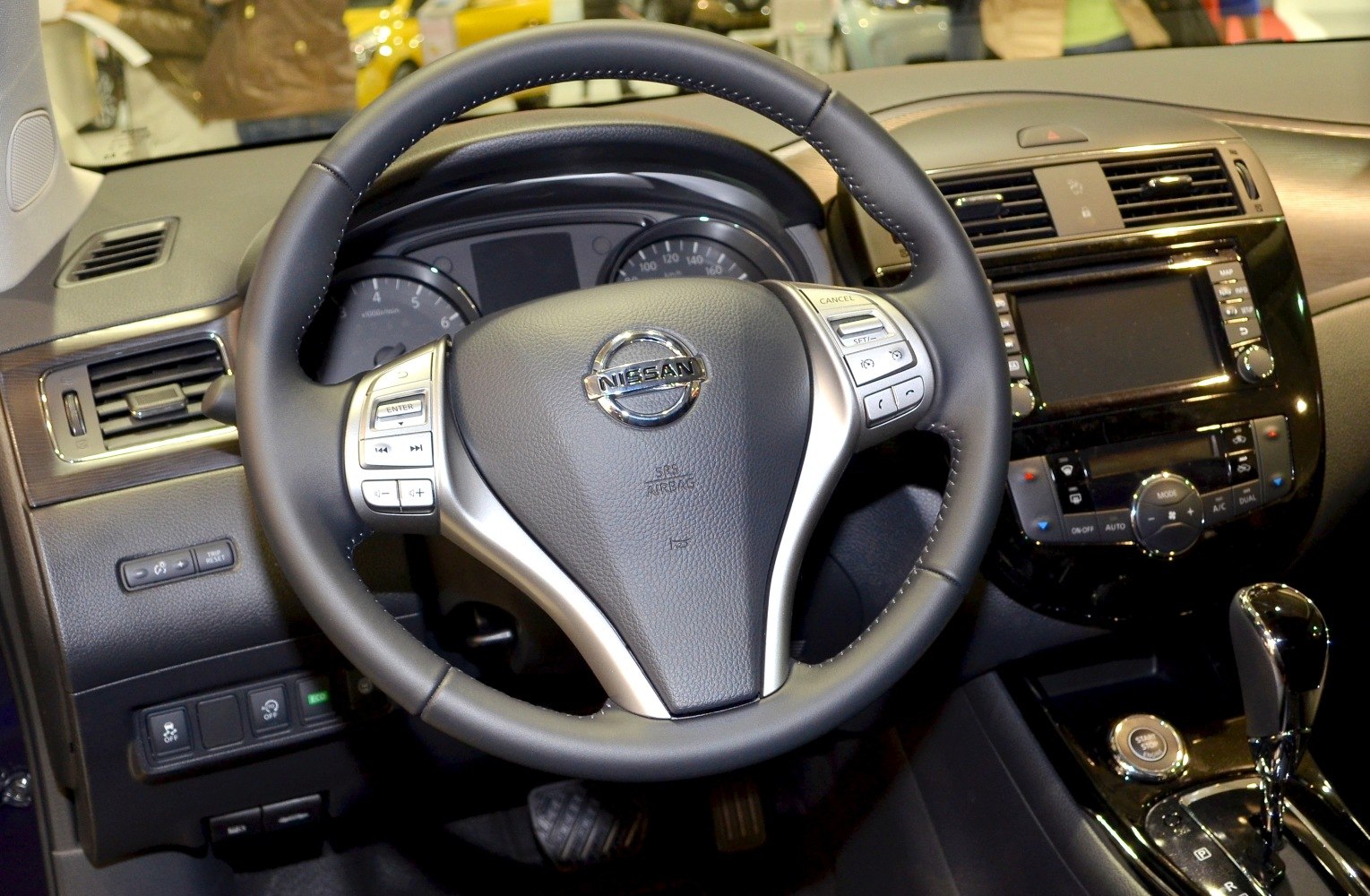 Steering wheel with control buttons and dashboard with multimedia panel.