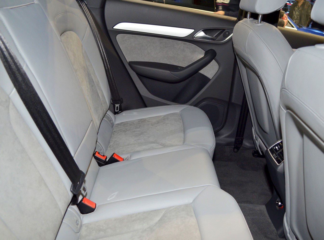 Rear seat interior with gray leather and suede upholstery, black seat belts, and door panel details.