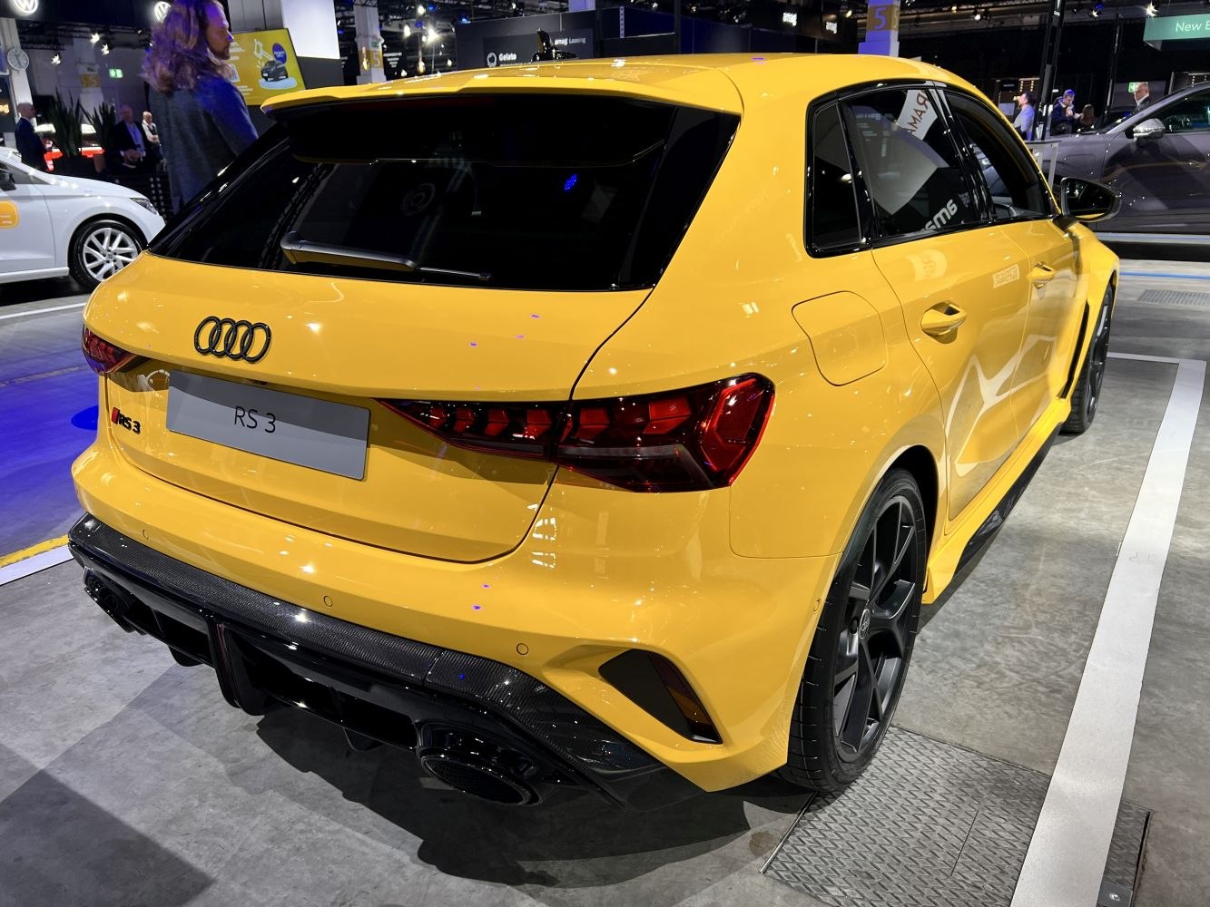 Rear and side view of a yellow sporty hatchback with dark alloy wheels