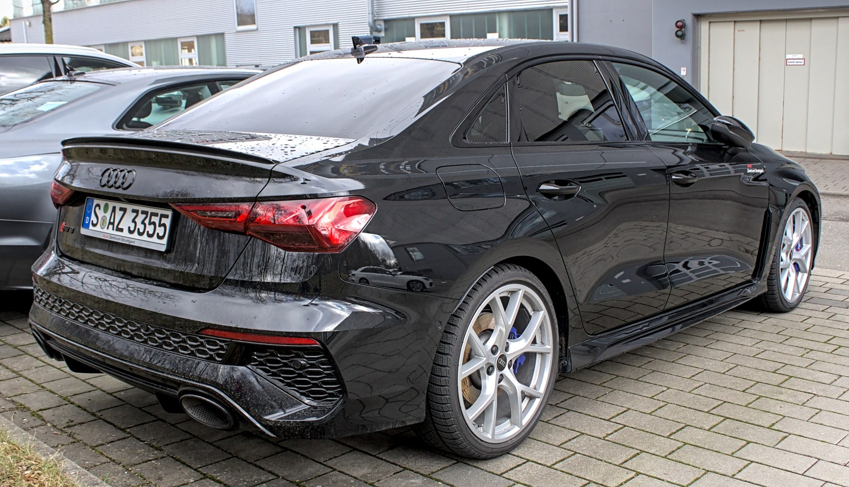 Rear and side view of black sporty sedan with distinctive lights and wheels