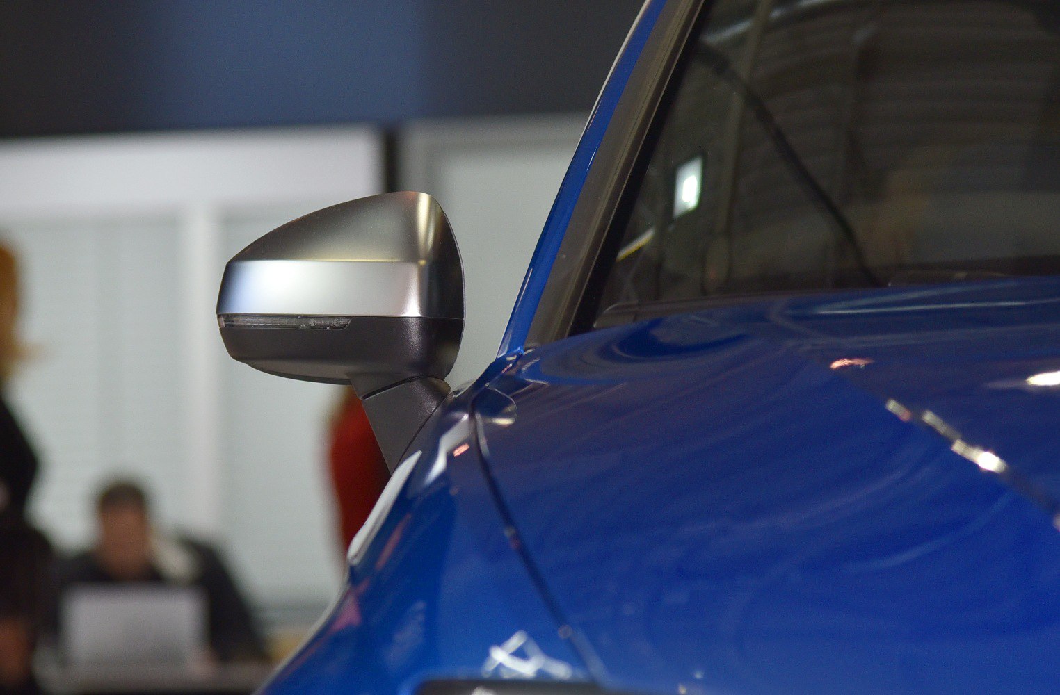Close-up of a silver side mirror on a blue vehicle.
