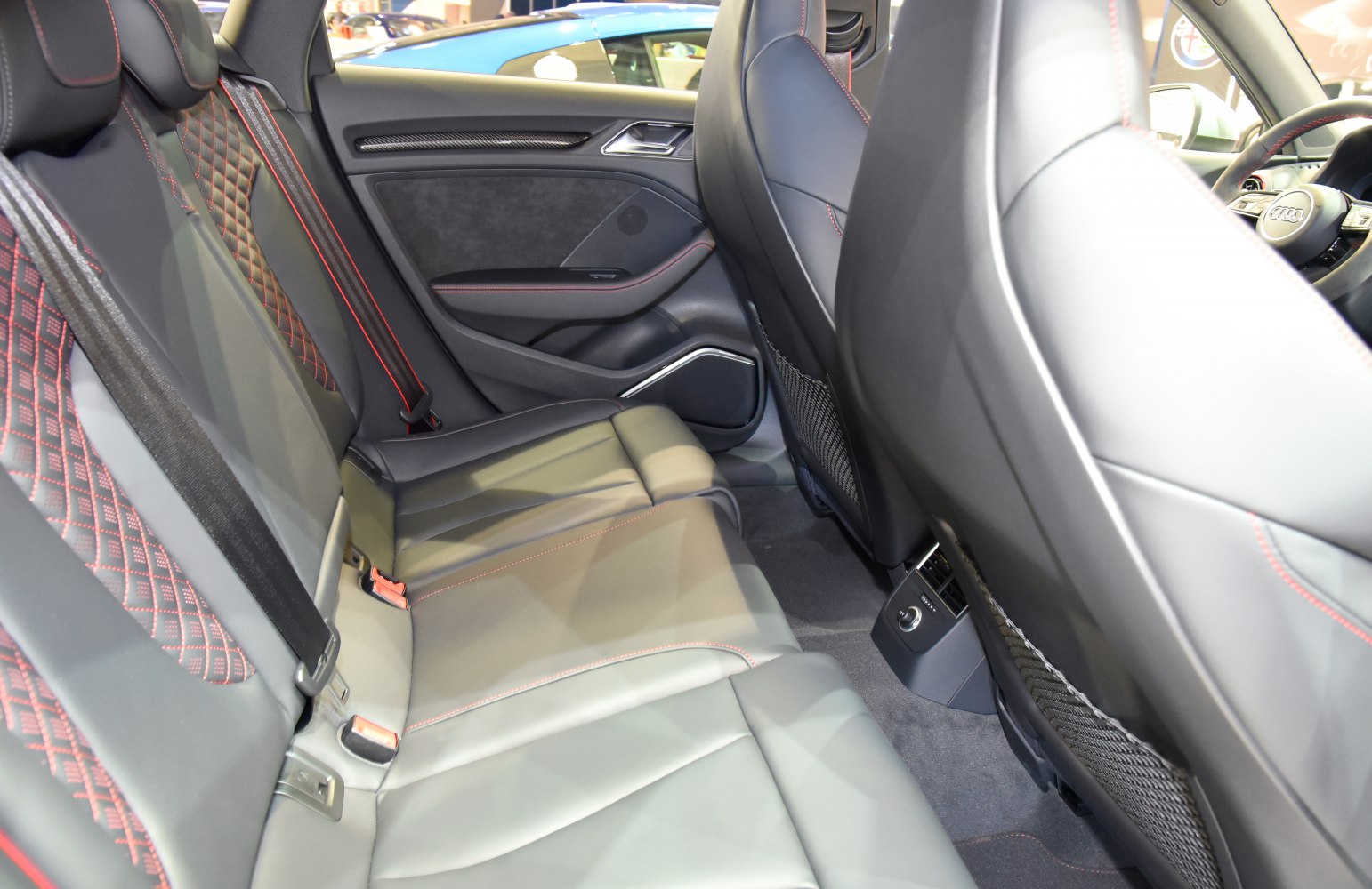 Rear seats with quilted stitching and red accents in a modern car interior.