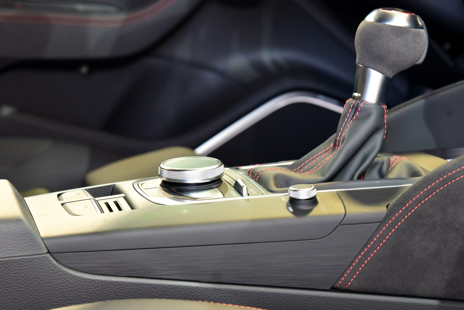 Gear shifter with red stitching and control knobs in car interior
