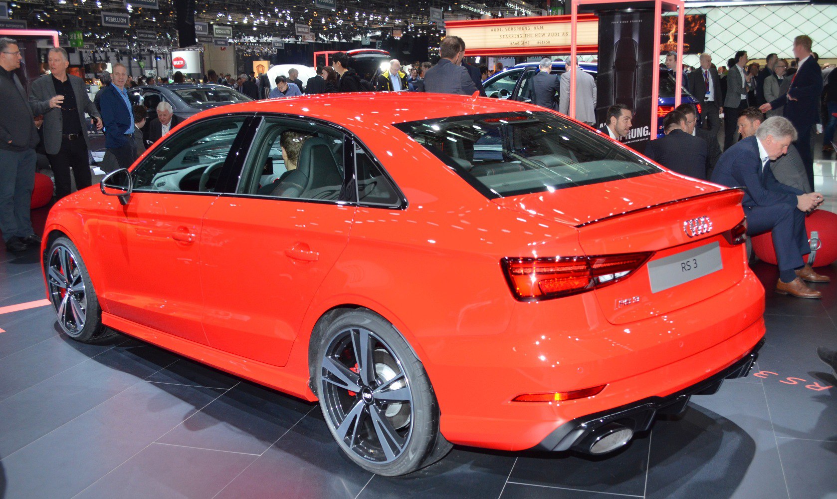 Rear-side view of sporty red sedan with alloy wheels