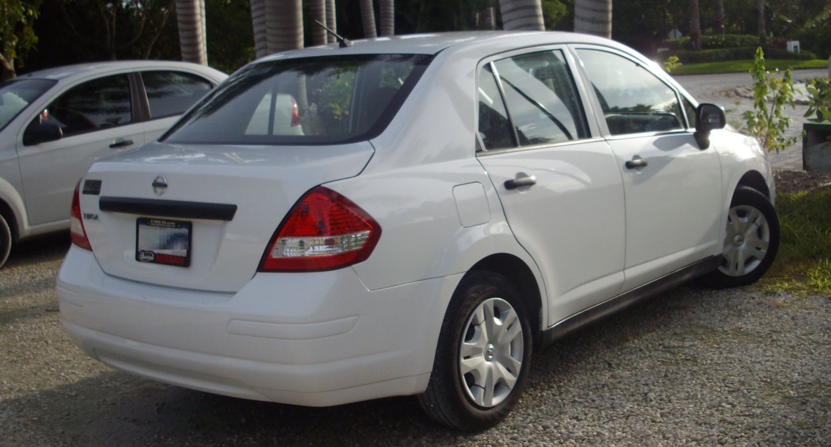 Rear side view of white sedan showing tail lights and four doors