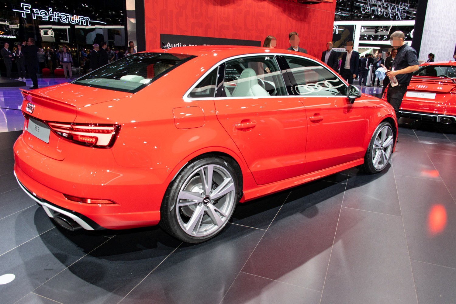 Rear and side view of red sedan with distinctive taillights and alloy wheels