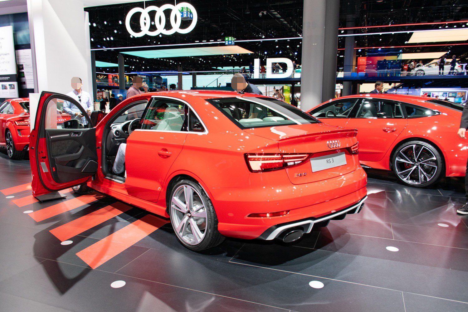Red sedan rear and side view with open driver door and alloy wheels
