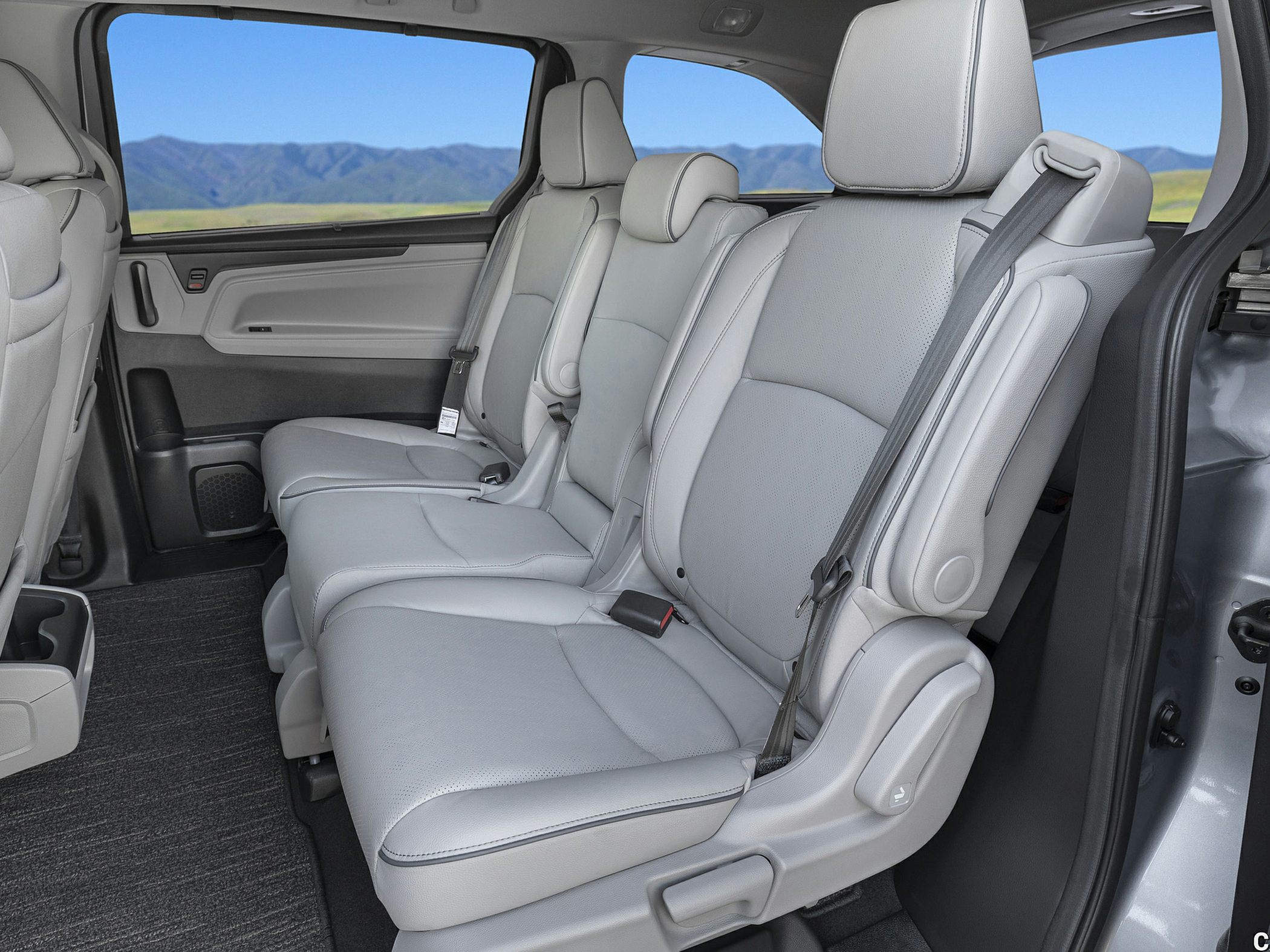 Spacious 2nd-row minivan seats with light upholstery and armrests