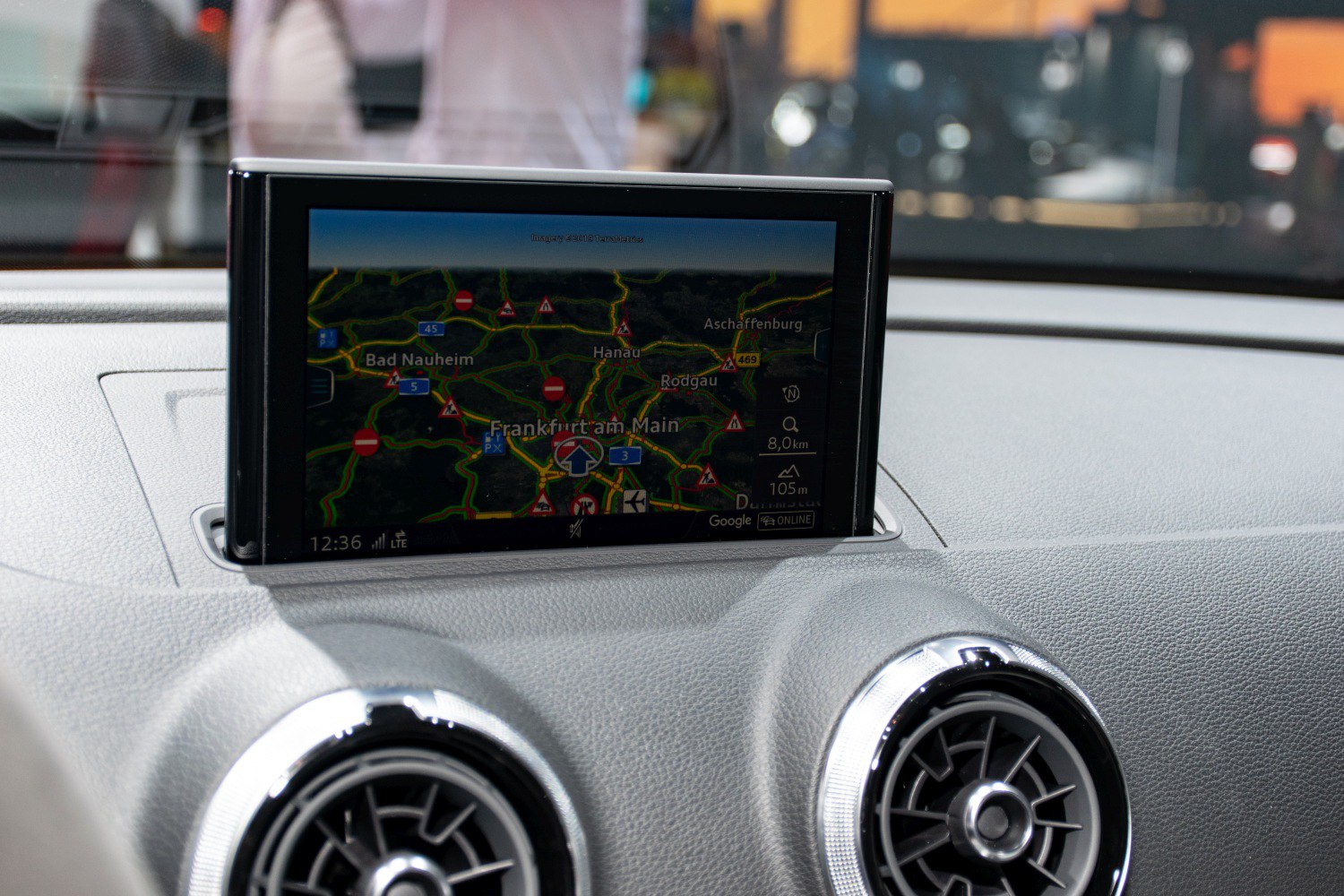 Infotainment screen displaying navigation map and circular dashboard air vents
