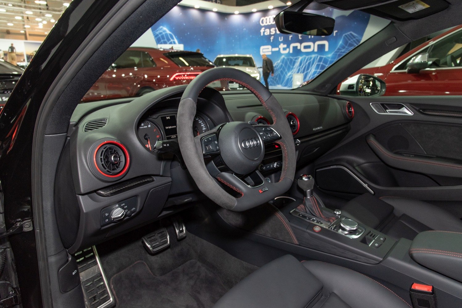 Sporty steering wheel with red-accented air vents in luxury sedan interior