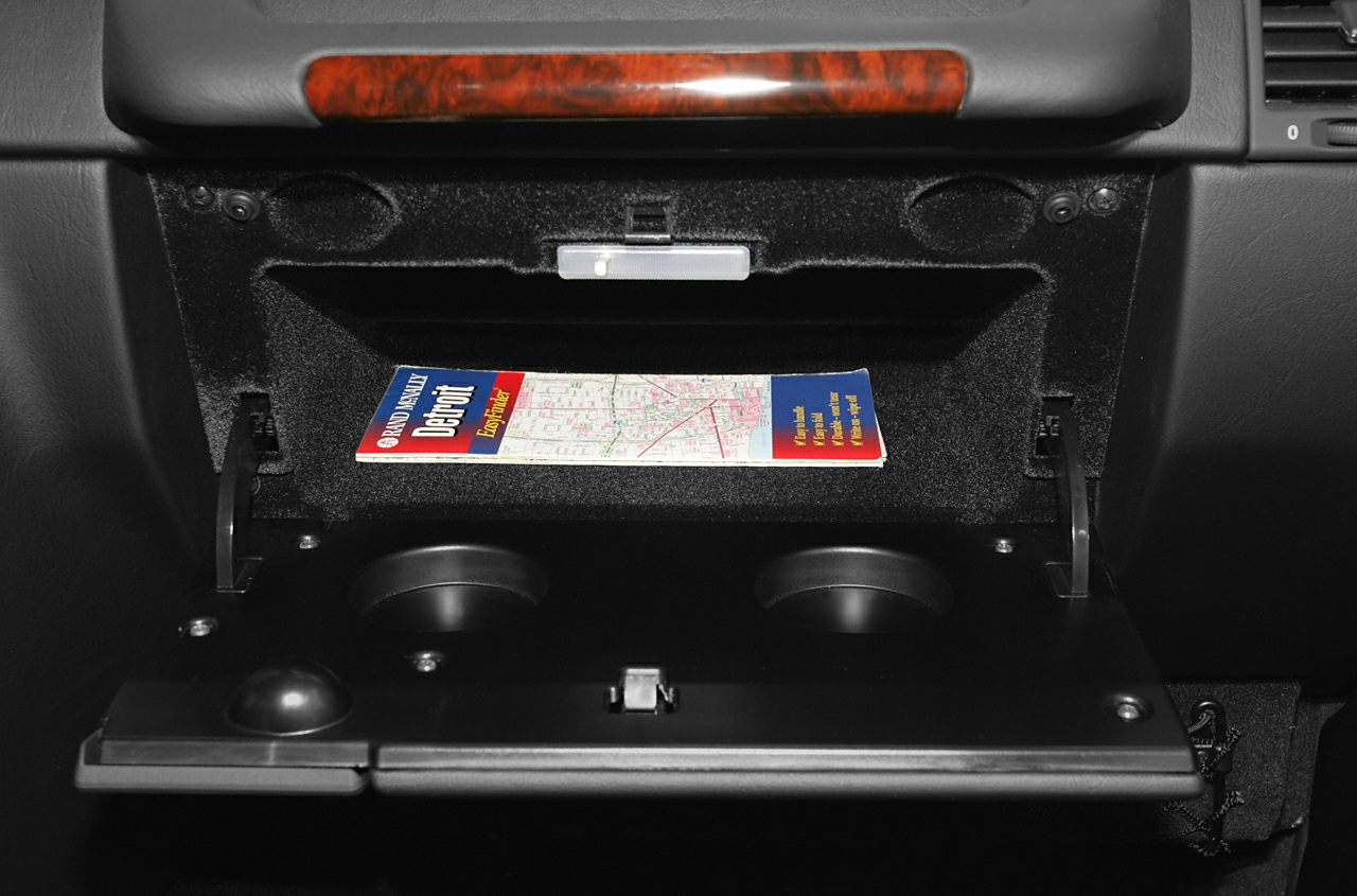 Open glovebox with cup holders and a map inside
