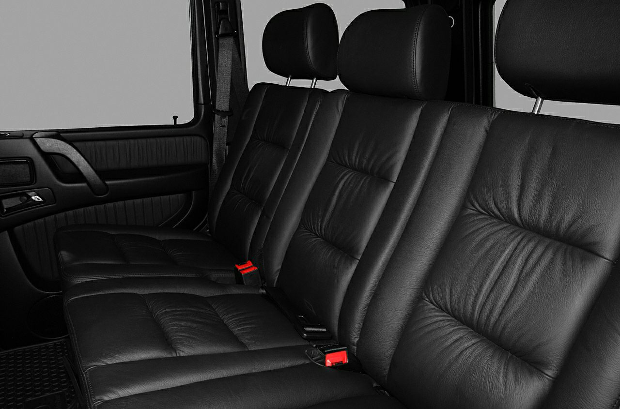 Rear black leather seats with headrests and red seatbelt clasps