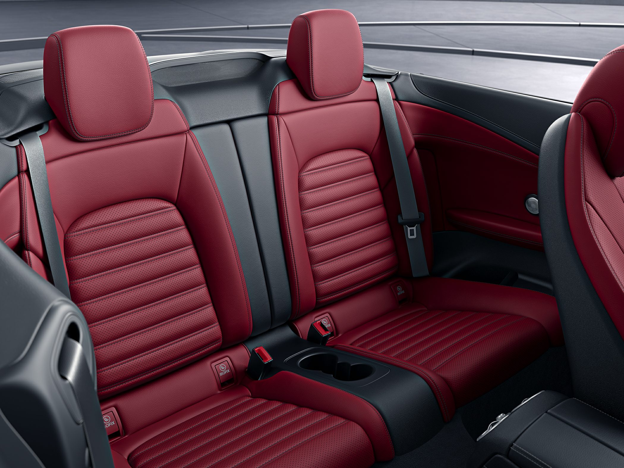Red leather rear seats with seatbelts and cup holders in a convertible.