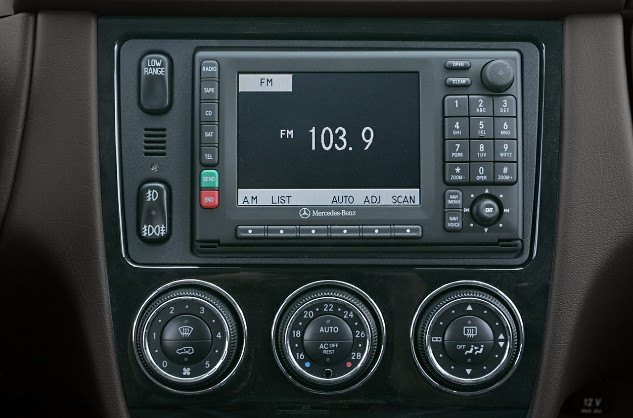 Close-up of a vintage car radio and climate control unit with dials and digital display