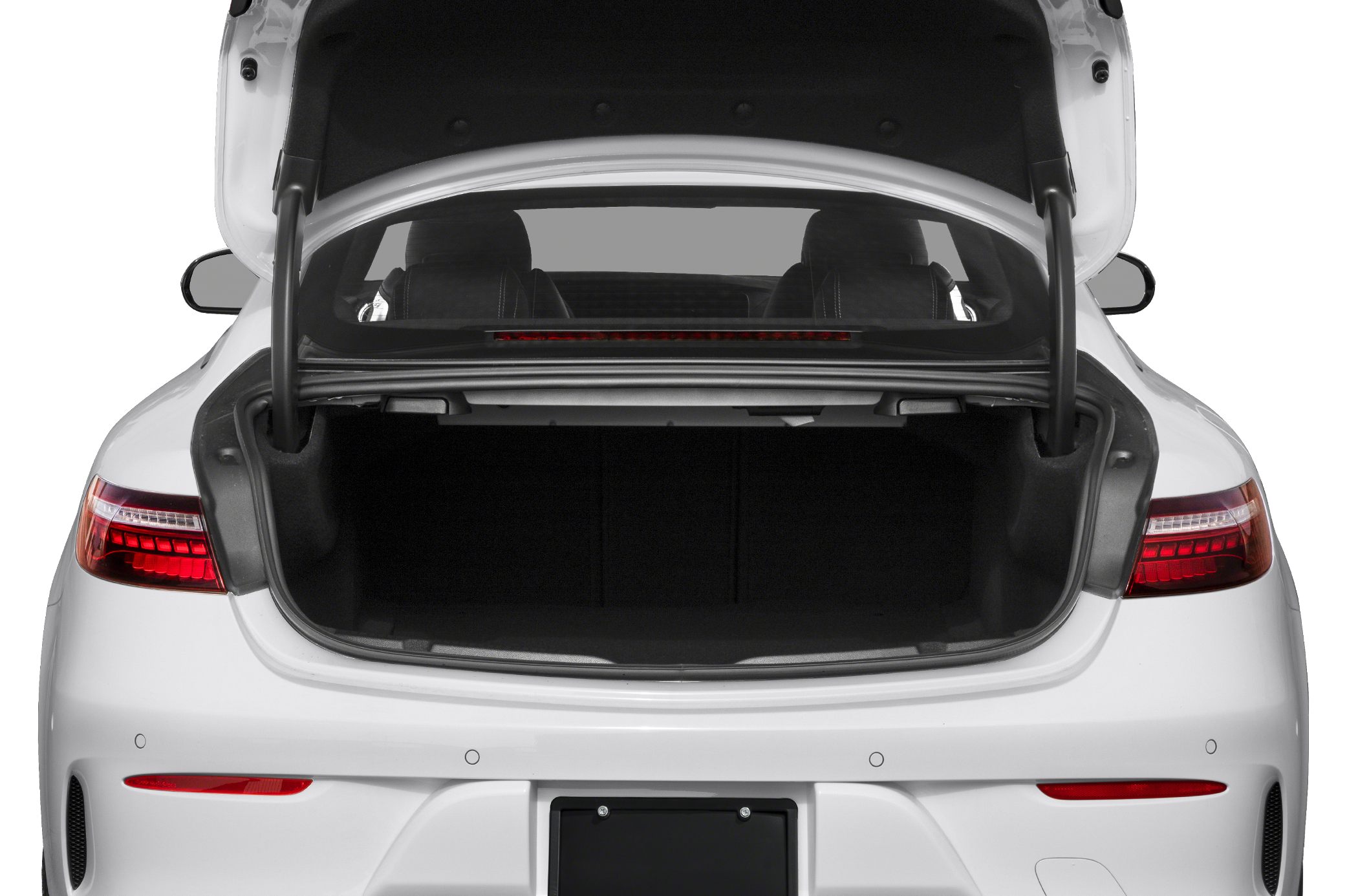 Open trunk of a white luxury coupe with visible rear seats and modern tail lights