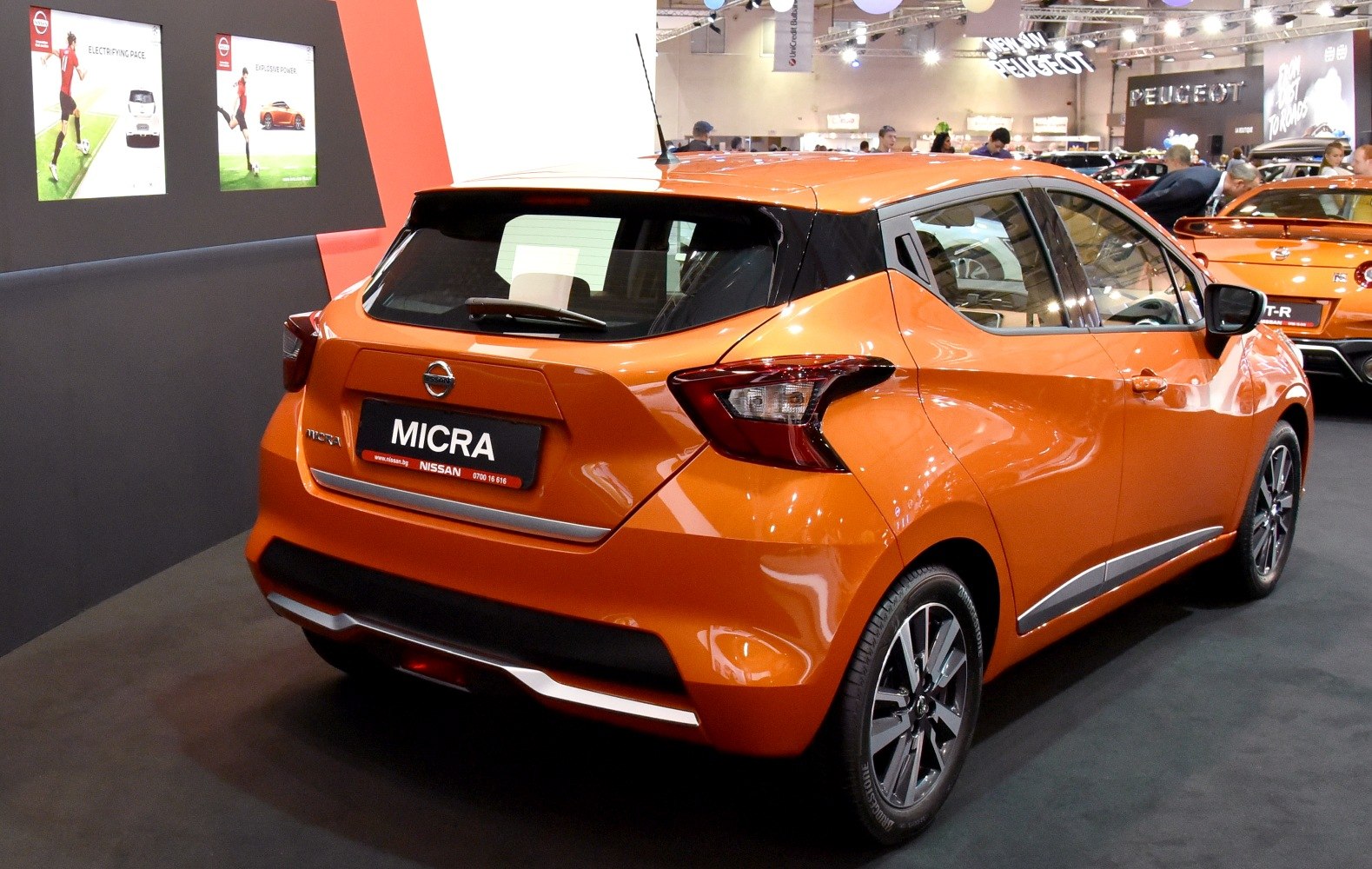 Rear three-quarter view of an orange hatchback with distinct taillights and sporty design