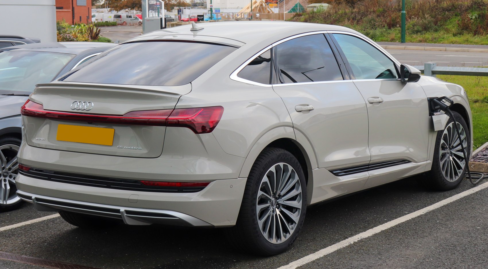 Rear-side view of electric SUV charging with LED tail lights and alloy wheels