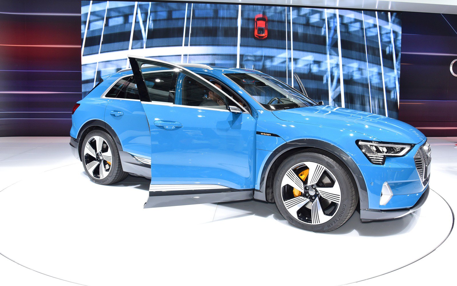 Electric SUV side view with open front door and distinctive alloy wheels