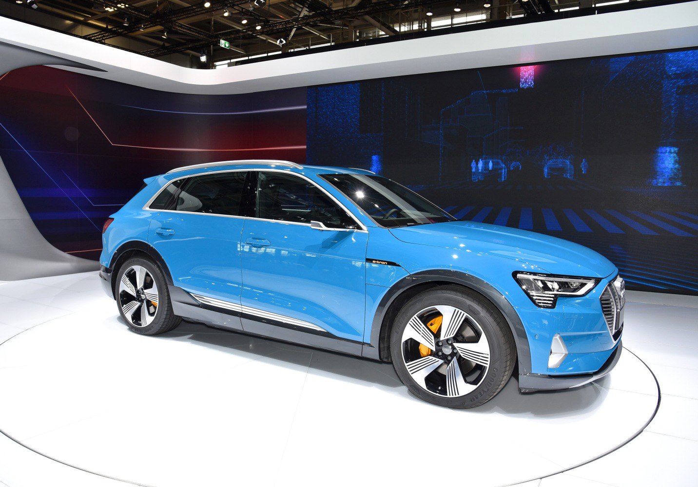 Blue electric SUV with futuristic alloy wheels and sleek aerodynamic design.