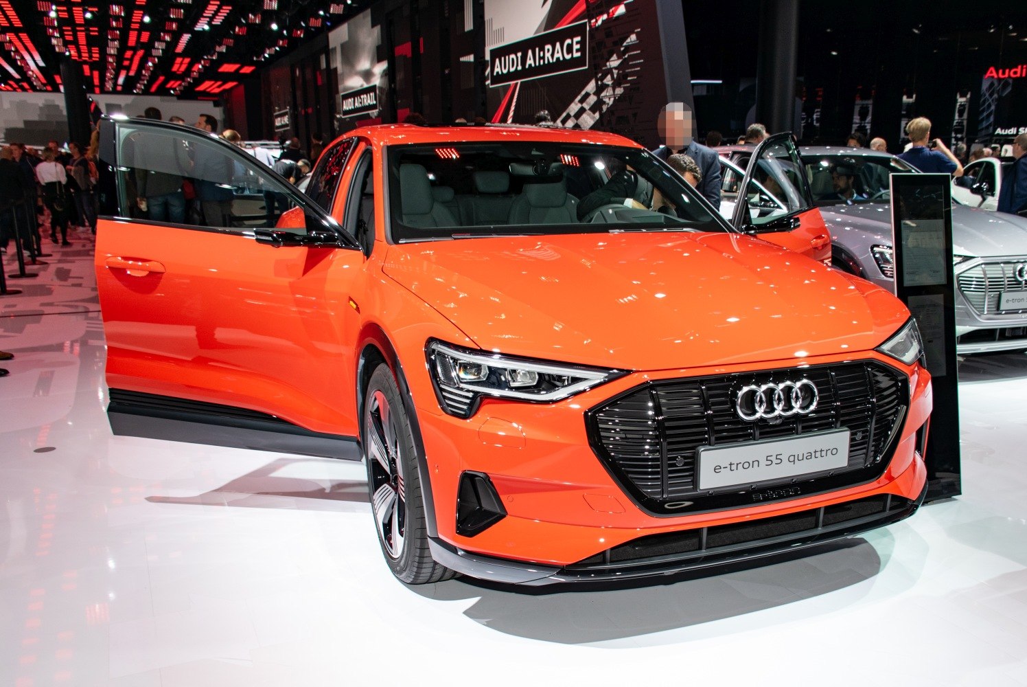 Bright orange electric SUV with LED headlights and open front doors