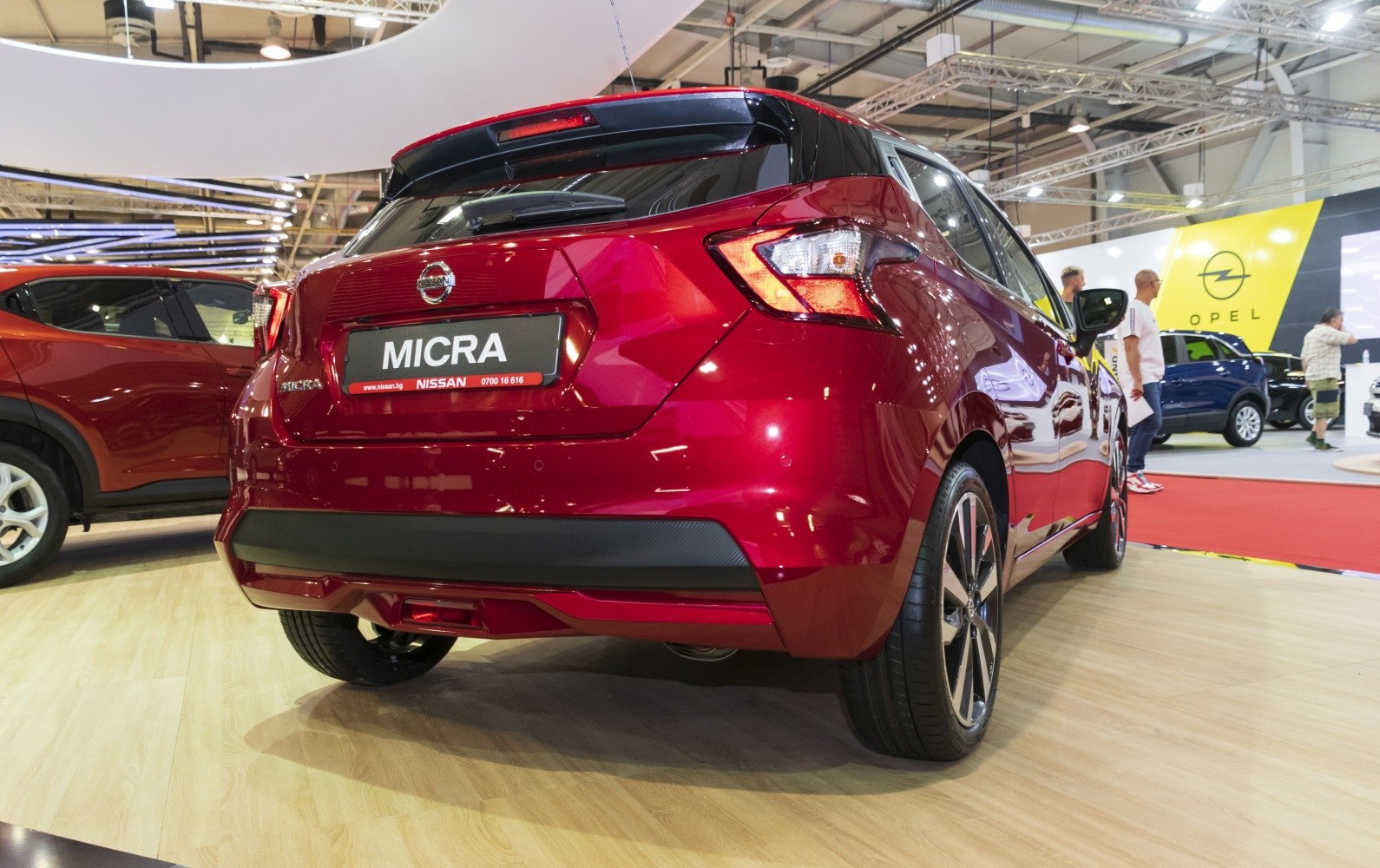 Red hatchback rear view with distinctive tail lights and alloy wheels.