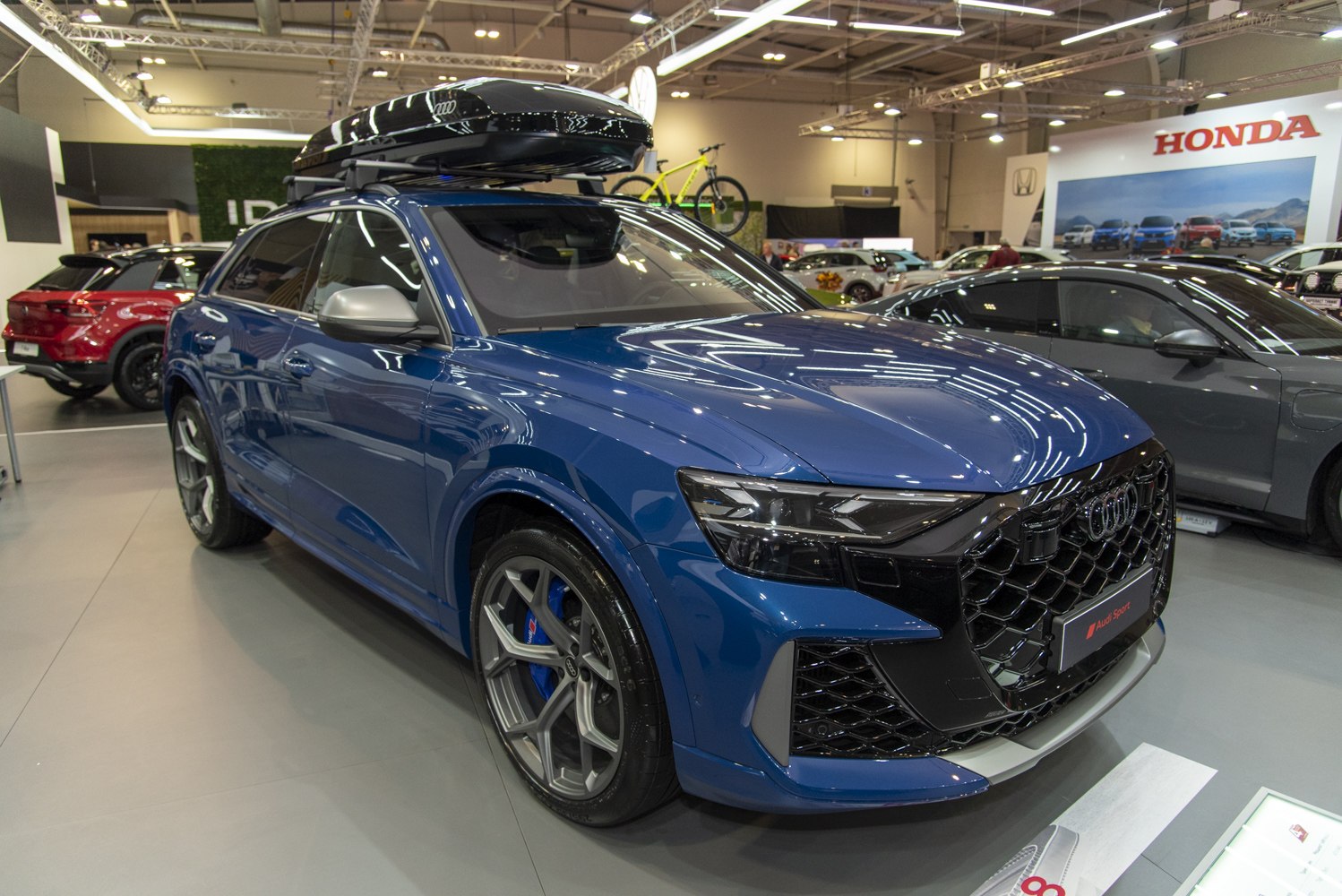 Large roof box mounted on blue luxury SUV with aggressive front grille