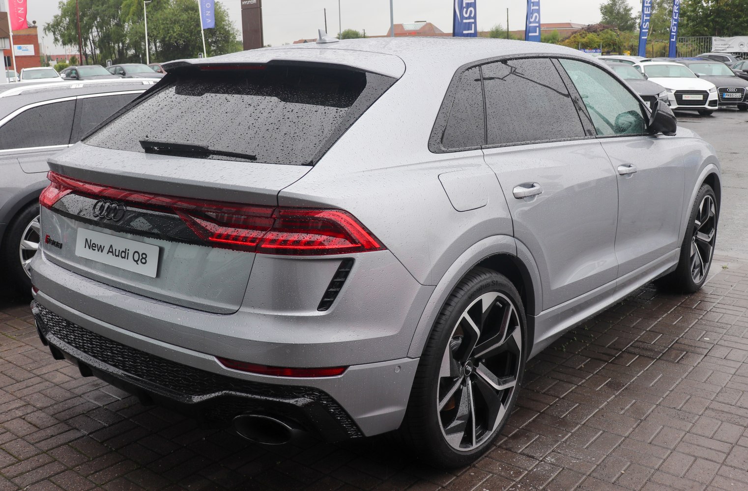 Rear LED tail lights and sporty alloy wheels of SUV in rain