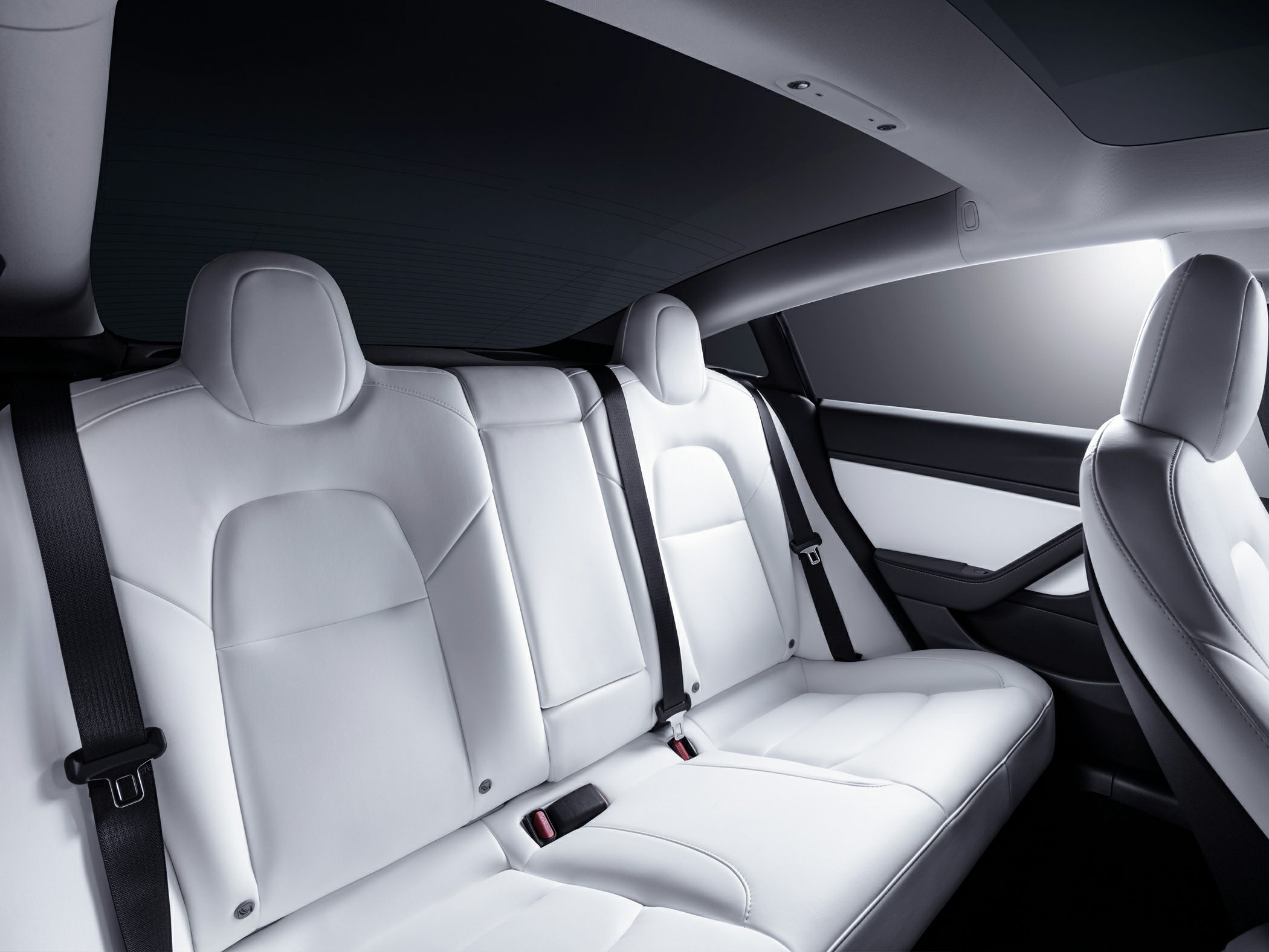 White rear seats with integrated headrests and black seatbelts