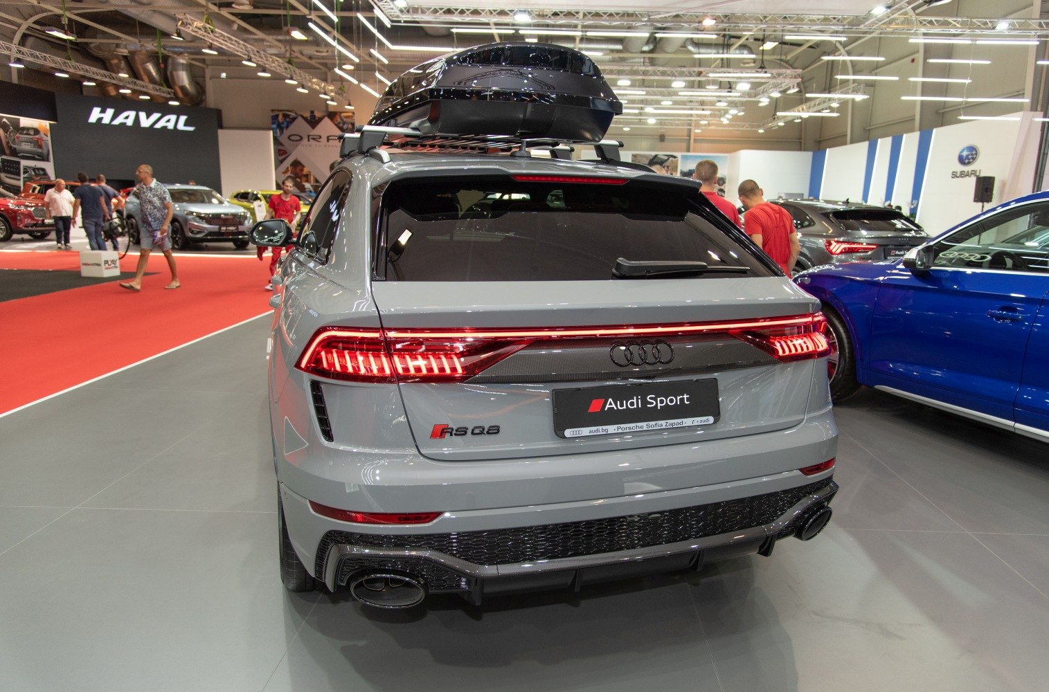 Rear view of sport SUV with roof box, illuminated taillights, and dual exhausts