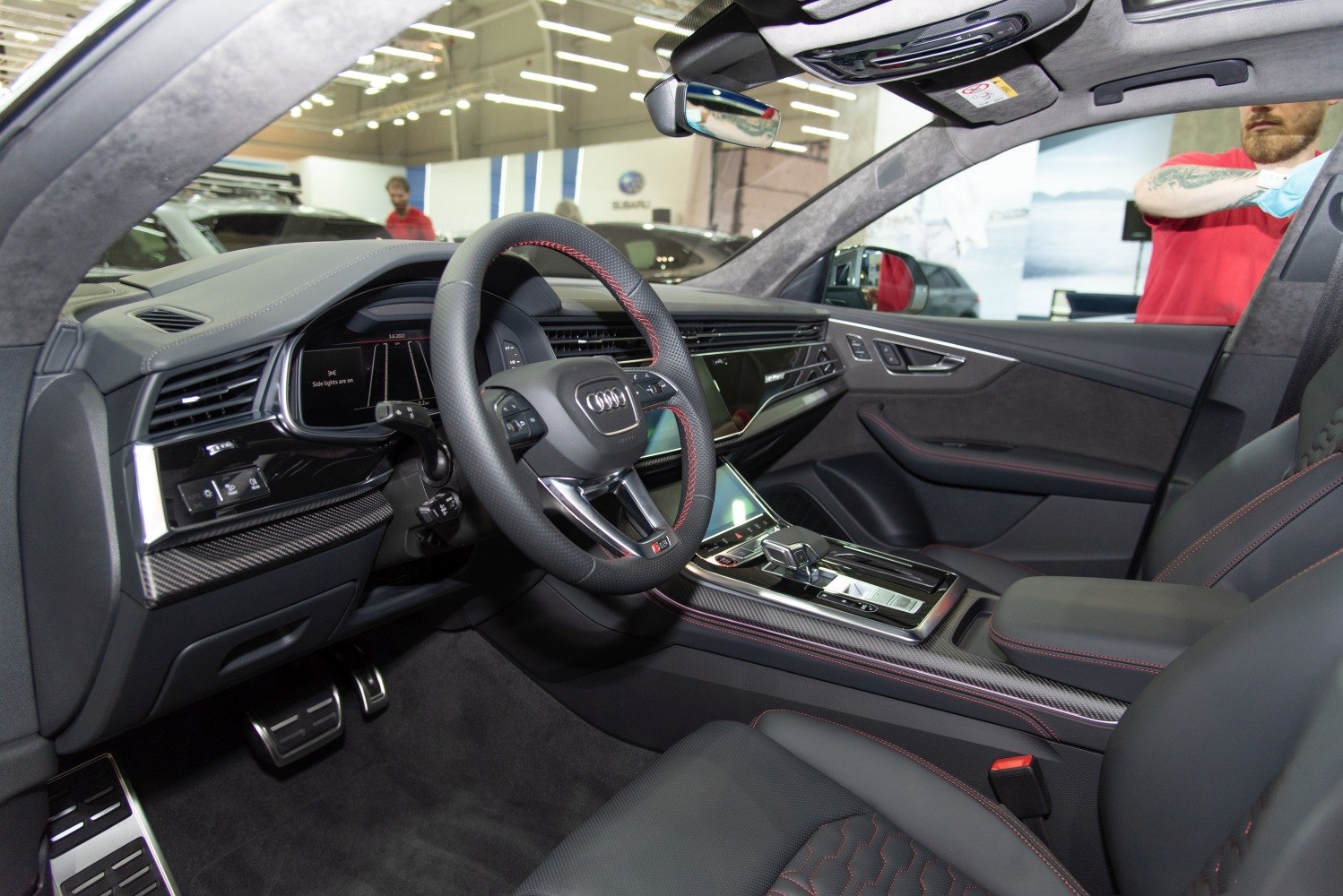 Luxury SUV interior with carbon fiber trim, digital display, and sport steering wheel.