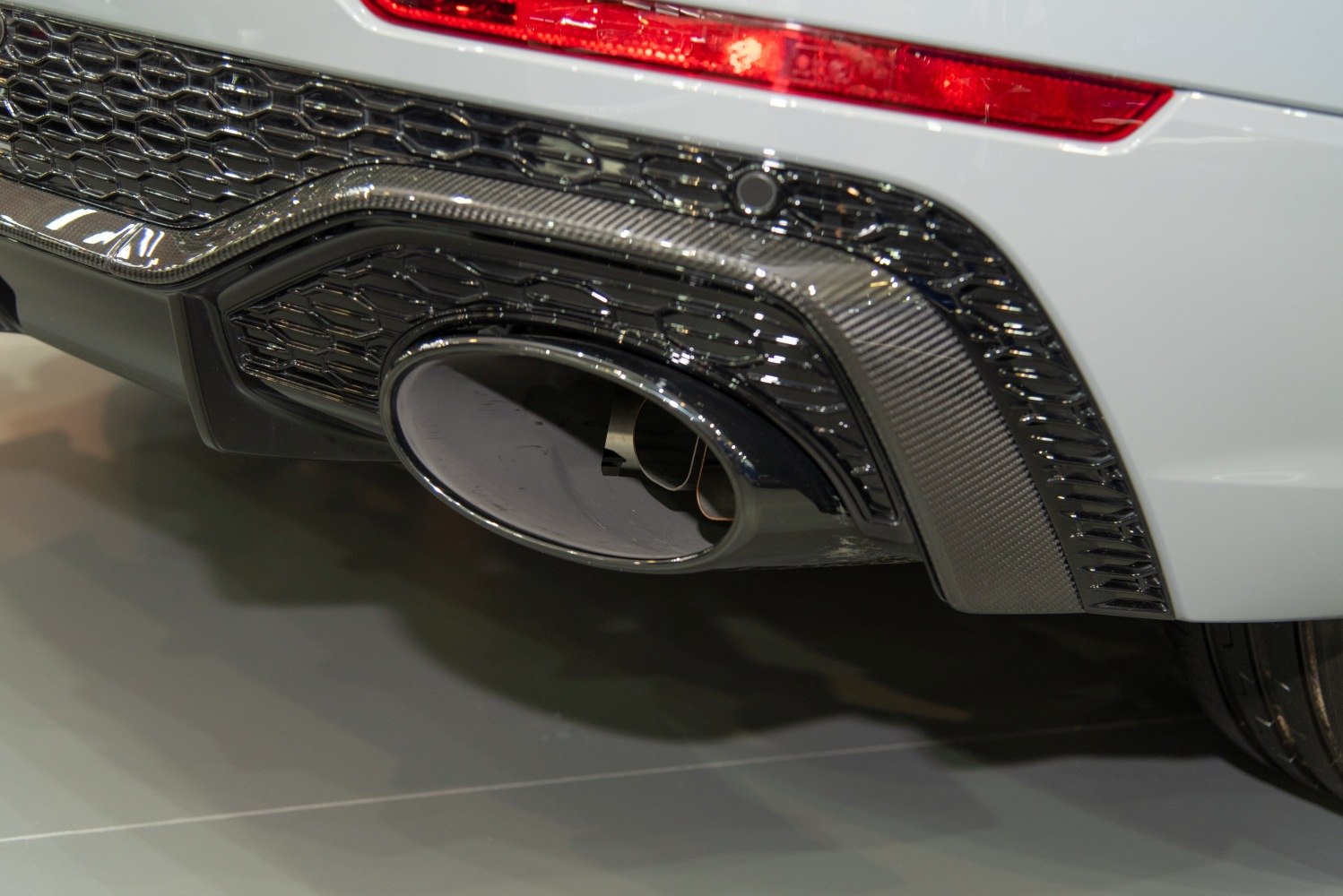 Close-up of large oval exhaust tailpipe and rear diffuser with carbon fiber trim