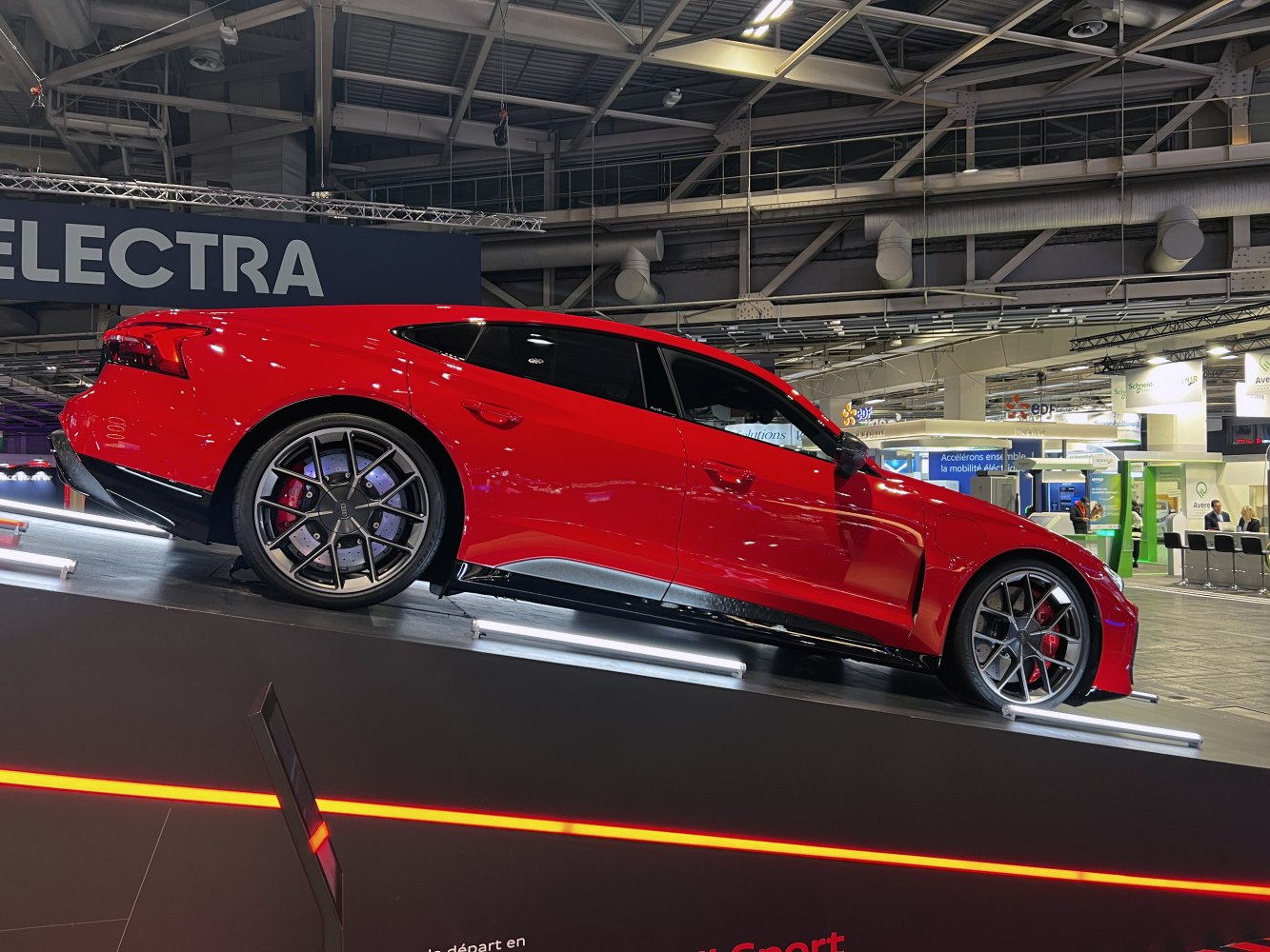 Sleek red electric sports car side profile with sporty alloy wheels indoors