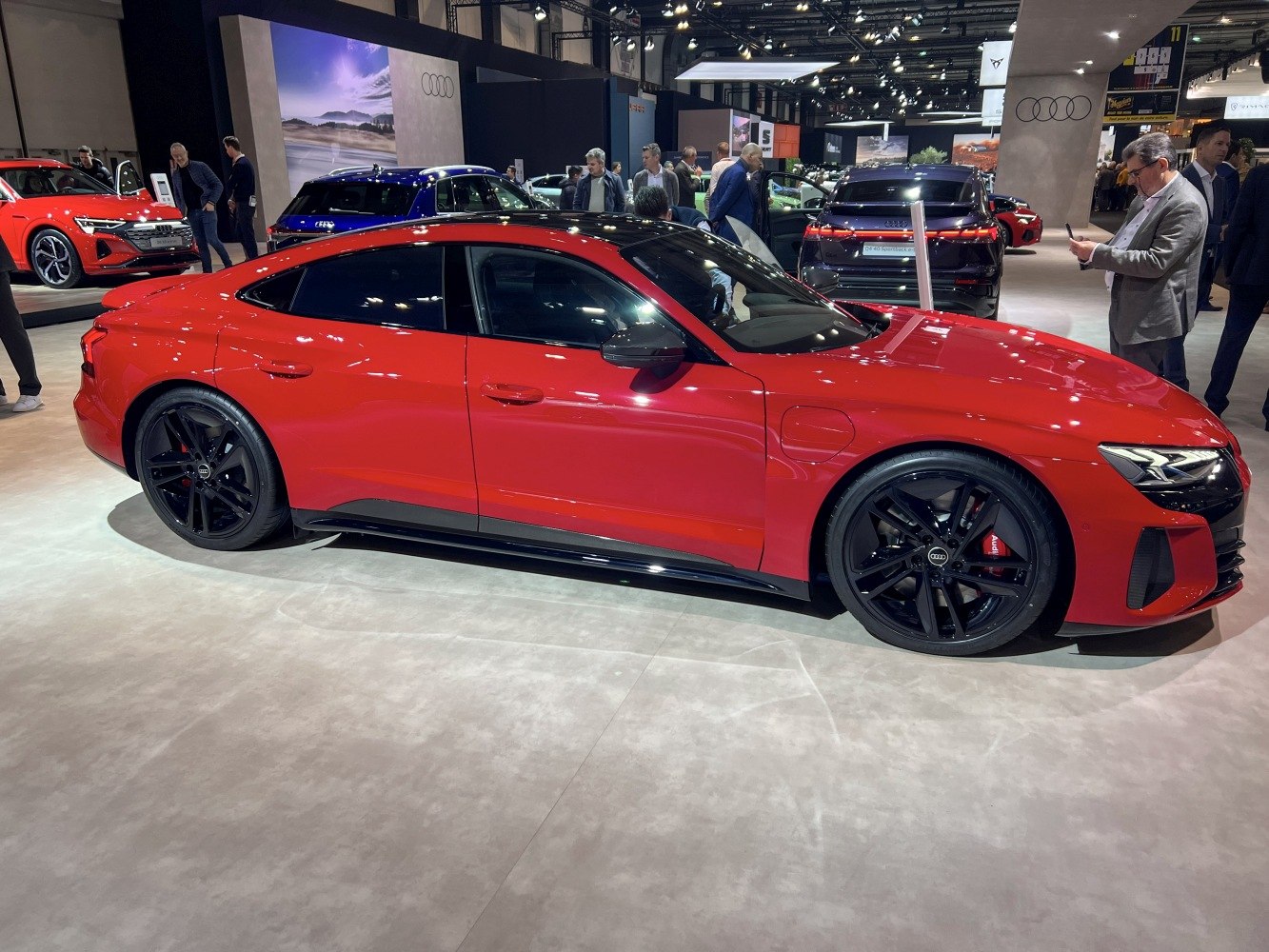 Red electric sports sedan with black wheels and roof in side profile