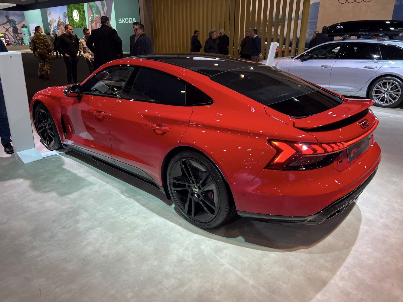 Red electric sports sedan rear side with black roof and aerodynamic design