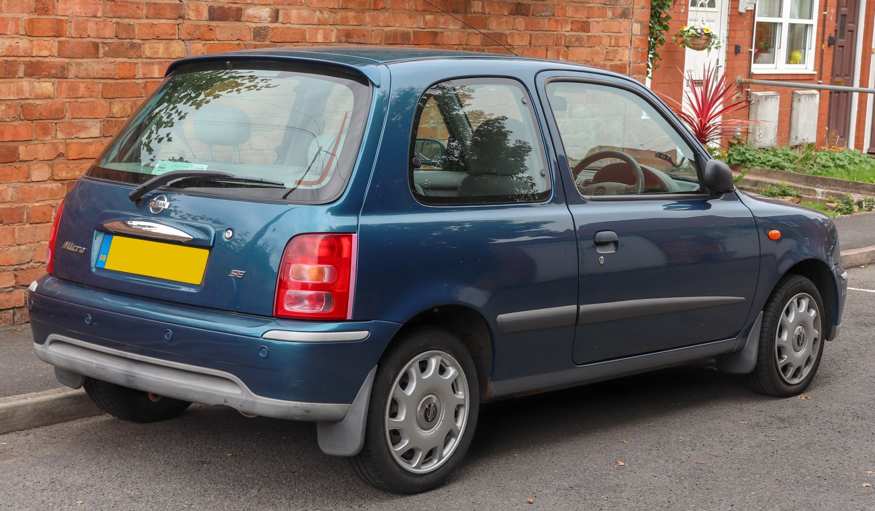 Rear-side view of a compact hatchback with alloy wheels and mudflaps.