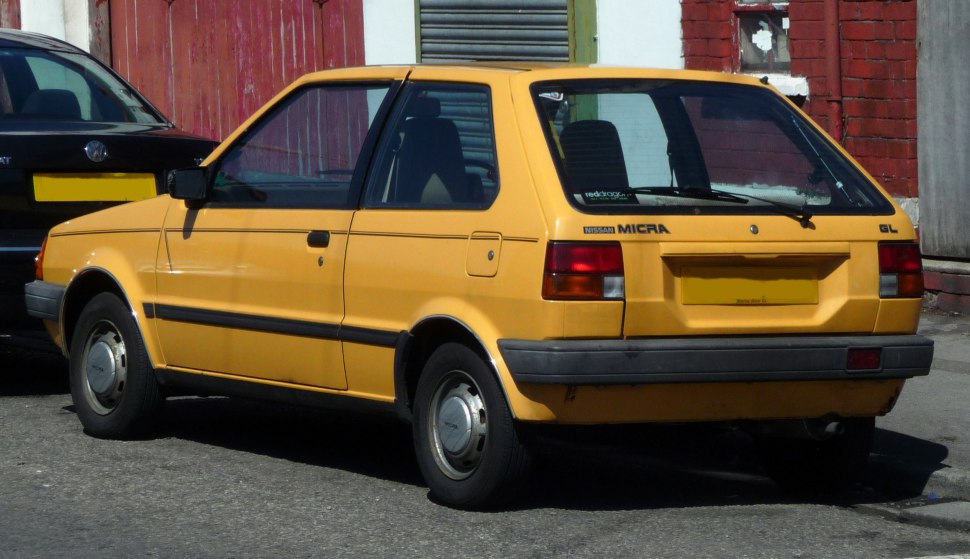 Rear side view of a yellow vintage small hatchback with classic 1980s styling