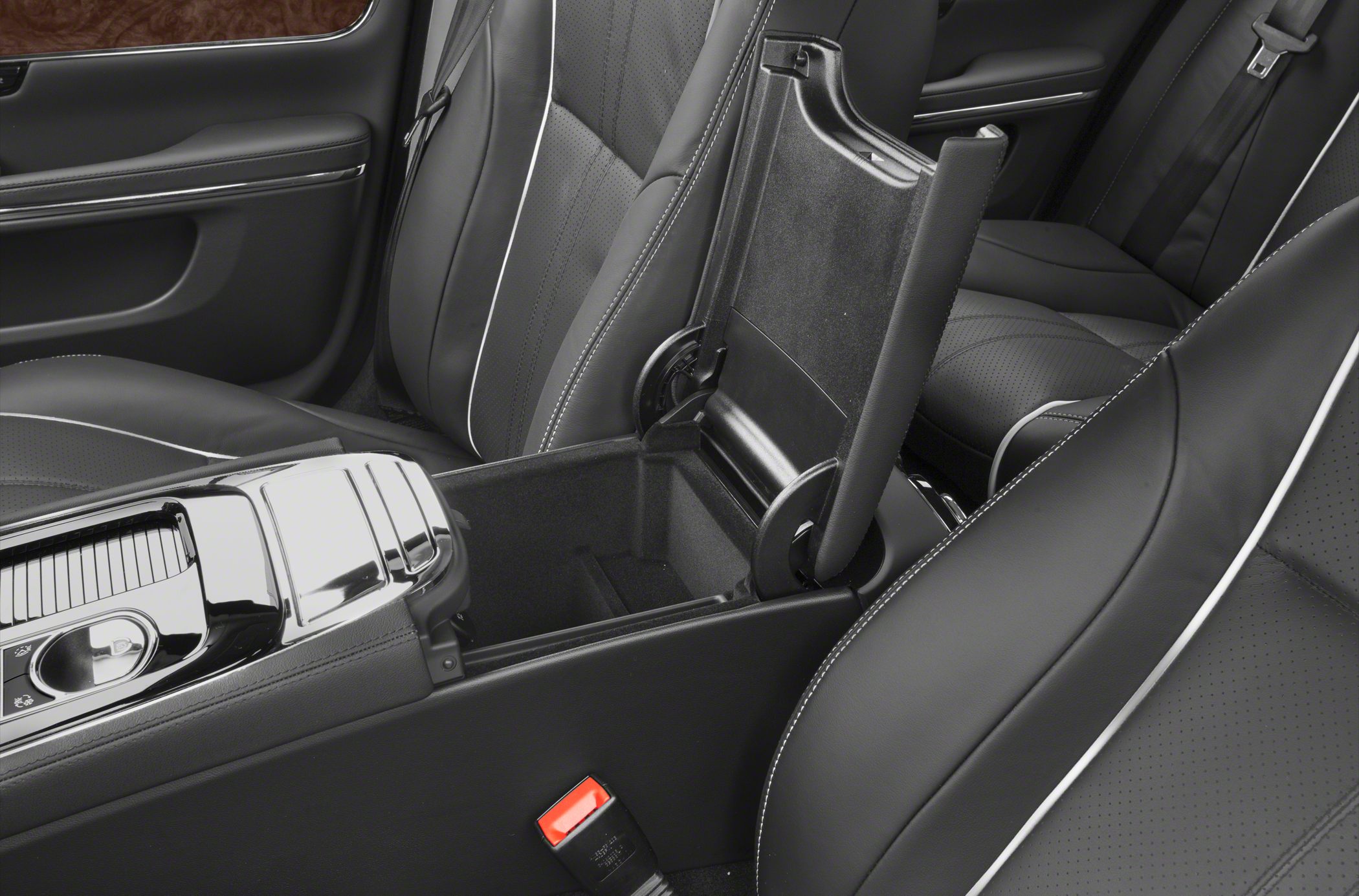 Black leather seats with white piping and open center console storage.