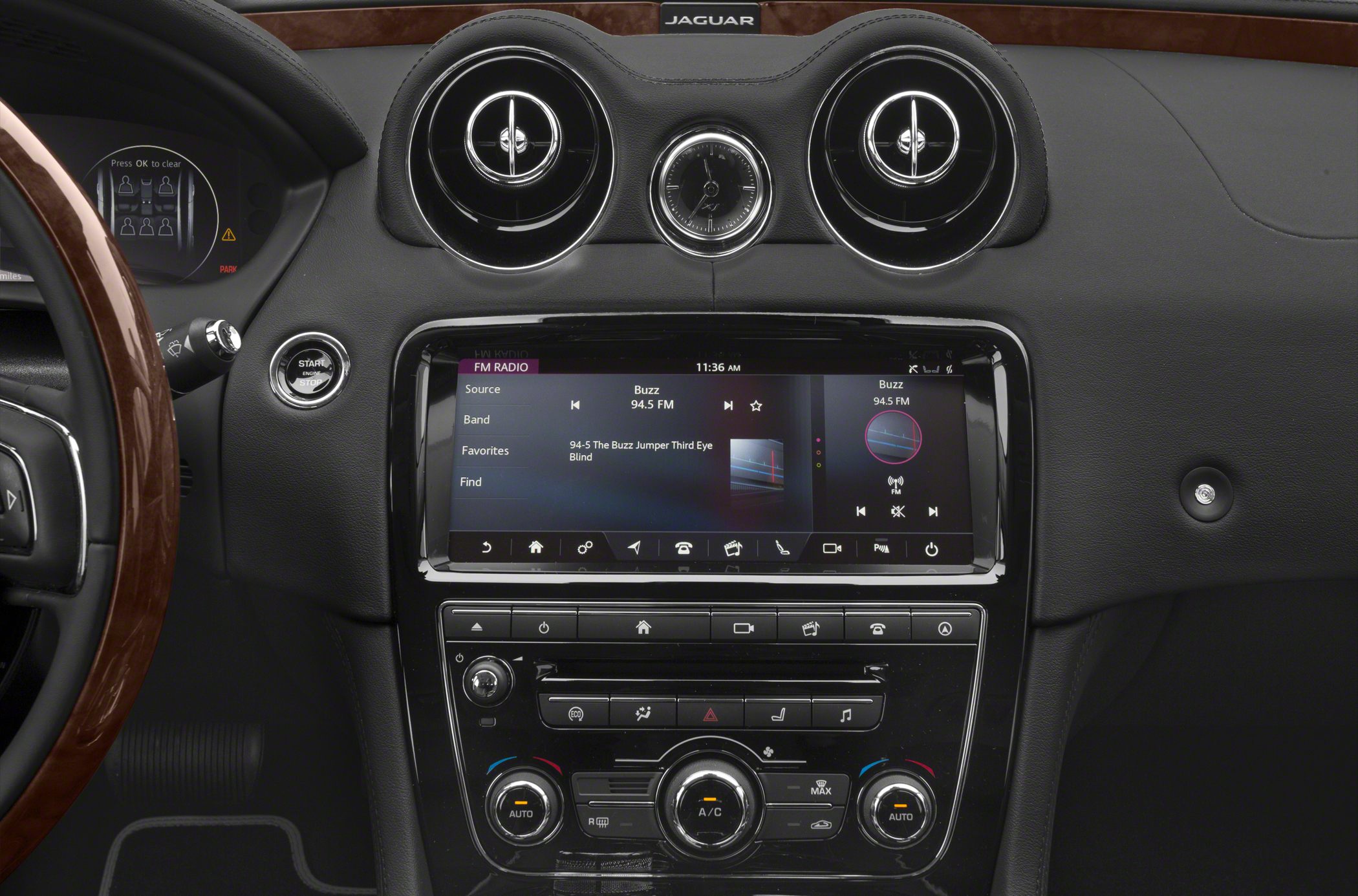 Luxury vehicle dashboard with analog clock, dual air vents, and touchscreen infotainment